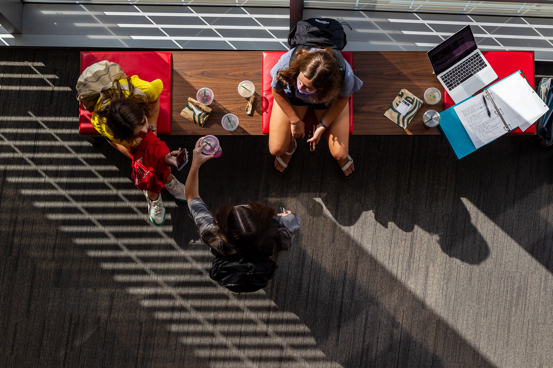 Students work on a bench in the Talley Student Union at NC State in Raleigh, N.C., Aug. 17, 2020. Many tables inside the union were taped off for social distancing measures in response to the coronavirus pandemic.