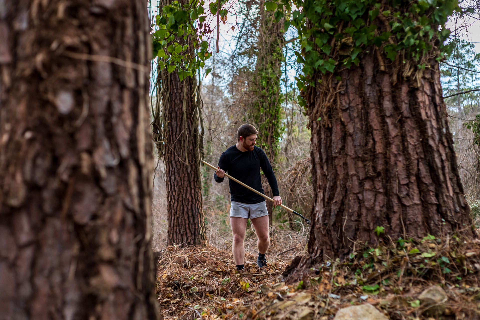 Patterson rakes leaves in the forest behind the home. At the base of the pine trees lie stones from an old set of stairs, likely built by John V. Allcott himself.