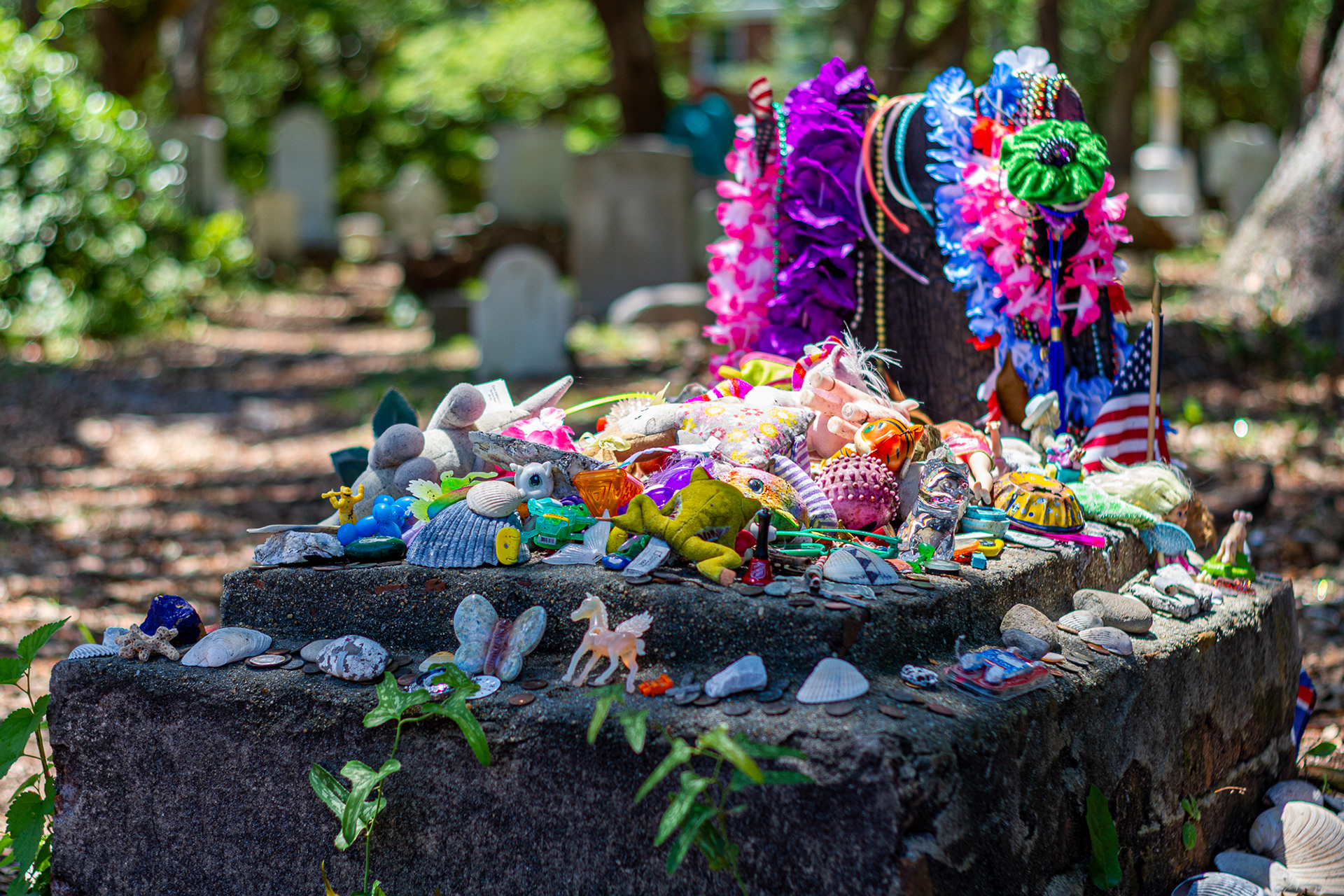 Toys, flowers, beads, and other trinkets adorn a small grave in the Old Burying Grounds or Beaufort, N.C., July 11, 2020. The grave belongs to the “Rum Keg Girl,” a young daughter who died from illness while returning from a voyage to England in the 1700’s. Although it was customary to bury bodies at sea, the father, who had promised his wife that he would bring the daughter home safely, insisted on bringing her body home.