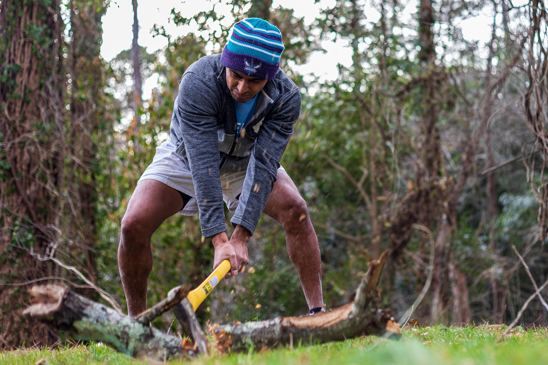 Neeral Patel chops a tree limb at his home in Chapel Hill, NC on Jan. 30, 2021. Behind him is a forest of trees densely covered in vines of English ivy and kudzu.