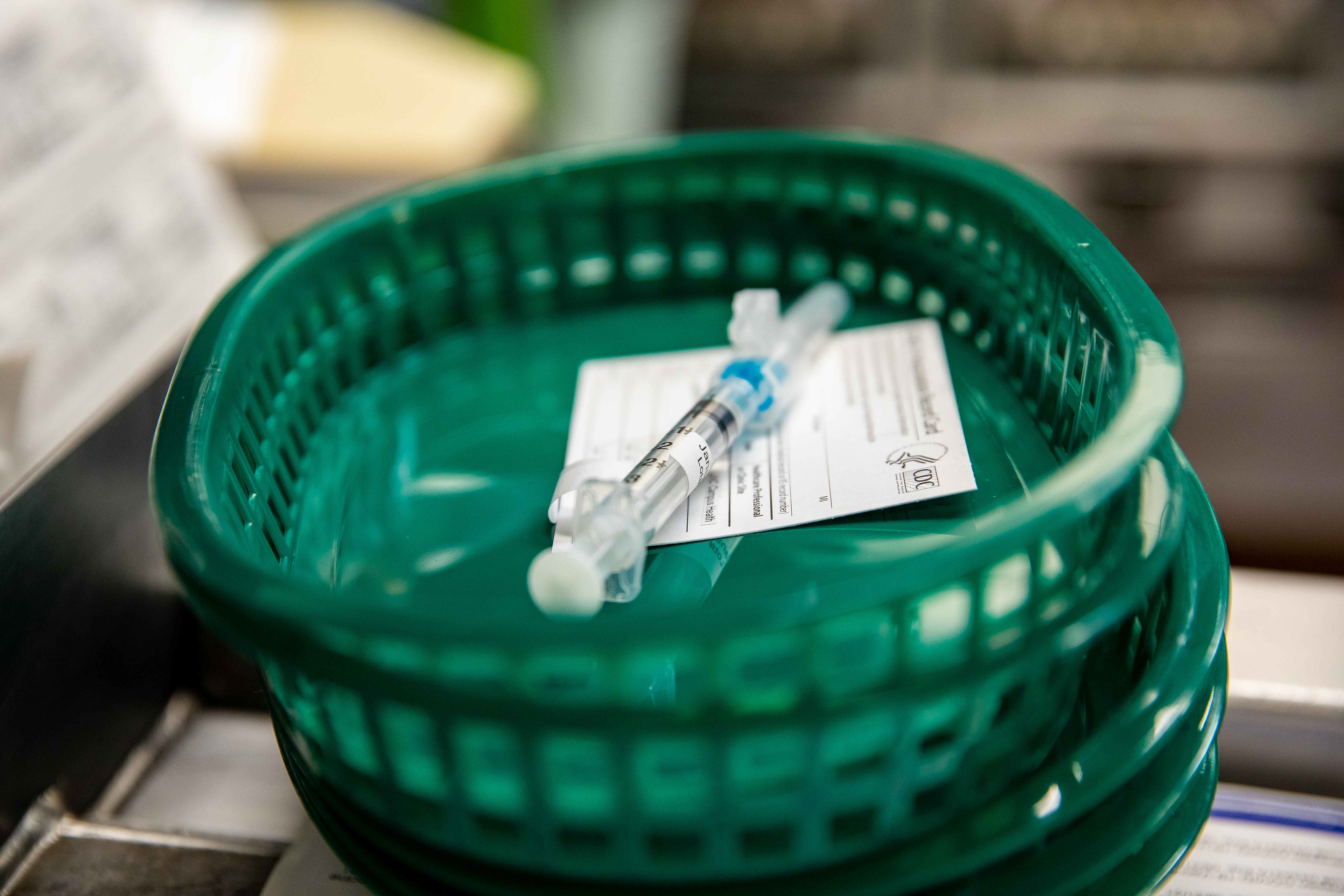 A vaccine dose lies ready to be administered along with a CDC vaccination card. The University has received 2,000 doses in its initial shipment of vaccines for students.