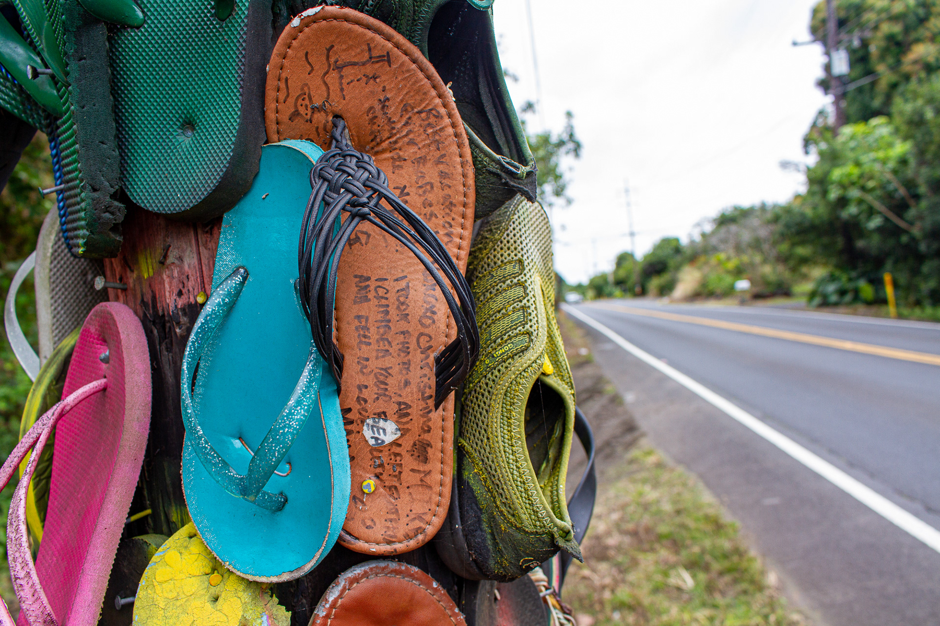 Dozens of flip-flops nailed to a telephone pole on the side of Highway 11 in Big Island, Hawaii.