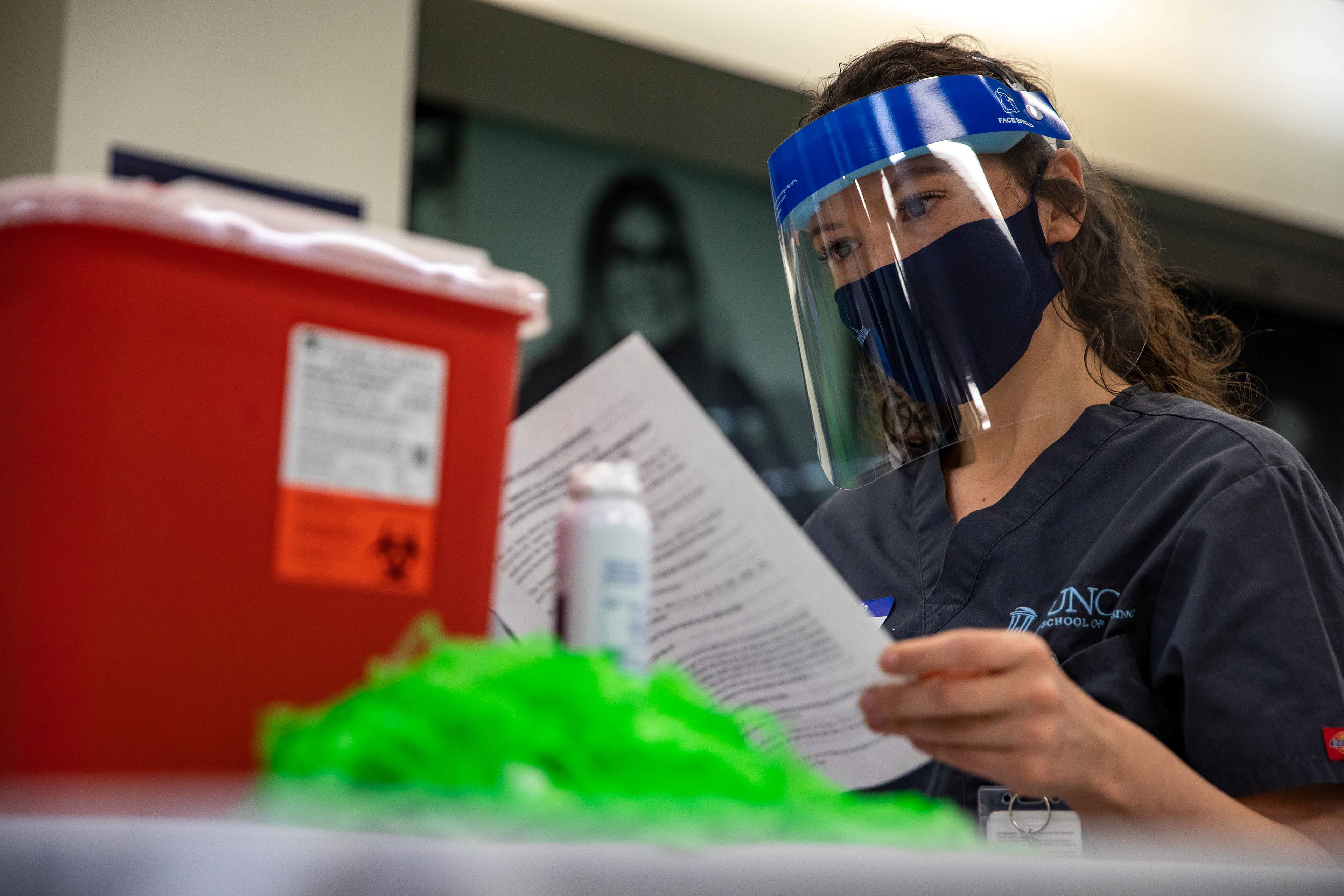 A vaccine administrator reads an information packet about the Johnson & Johnson vaccine.
