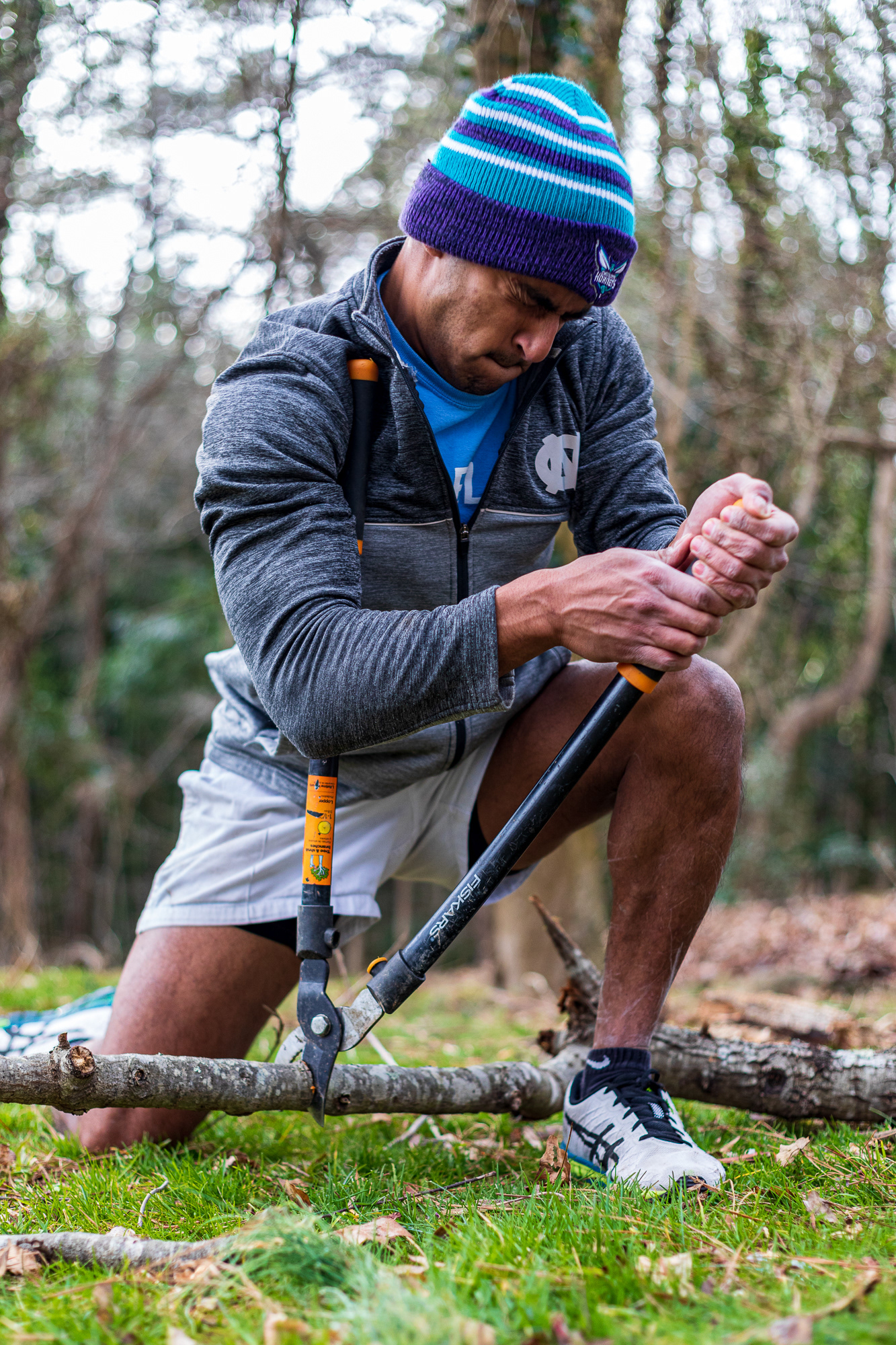 Patel fights to cut a branch with a branch clipper. With no power tools at their disposal, dealing with the mess of vines and dead trees at their home is a challenge.