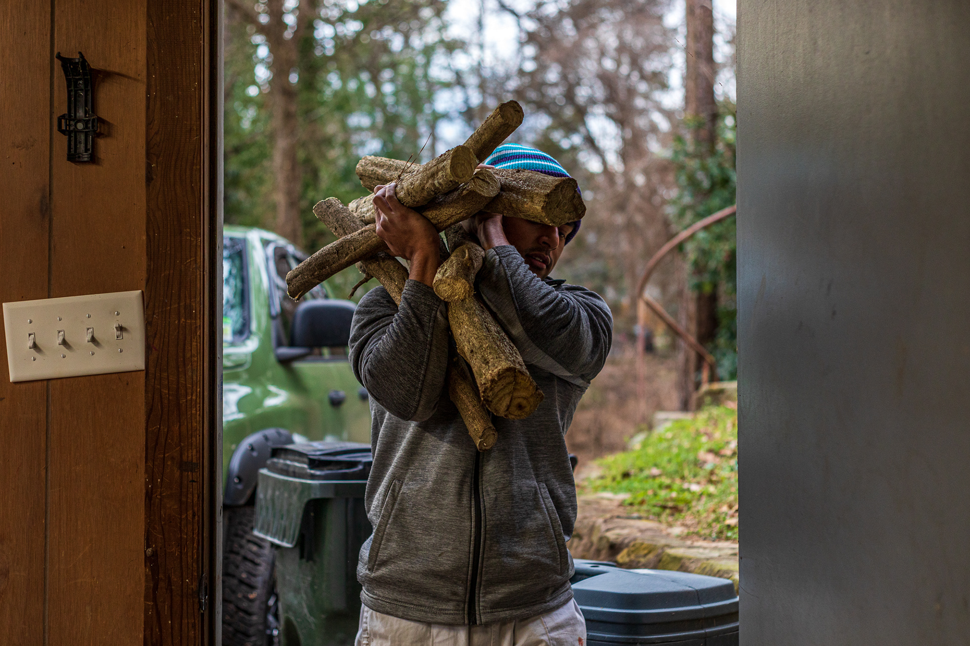 Patel carries a bundle of firewood into the basement of his home to dry. There, piles of tree branches and strands of ivy sit on top of a concrete floor covered in random droplets of paint – the likely remnants of an art studio.