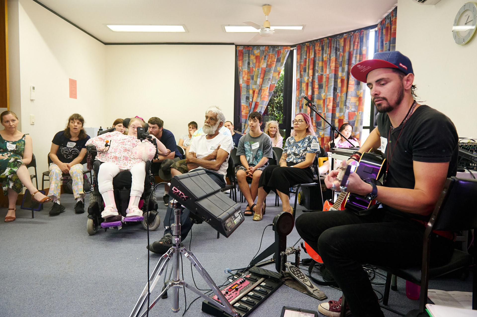 Josh Notting from Swoonsound Music School is playing a guitar during a workshop for Crossroad Arts Inc