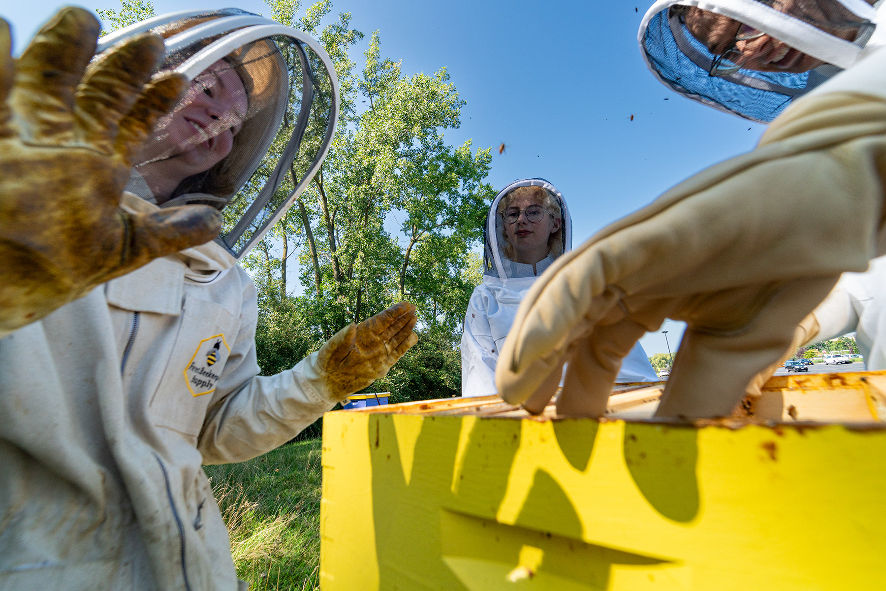 Ellie Warren, Emmett Beggs, and Isaac Southwell during the annual honey harvest at hives maintained by the RIT beekeeping club, on Sept. 3, 2023.  Warren signs to Beggs as they are a member of the National Technical Institute for the Deaf.  Warren is currently studying American Sign Language at RIT.