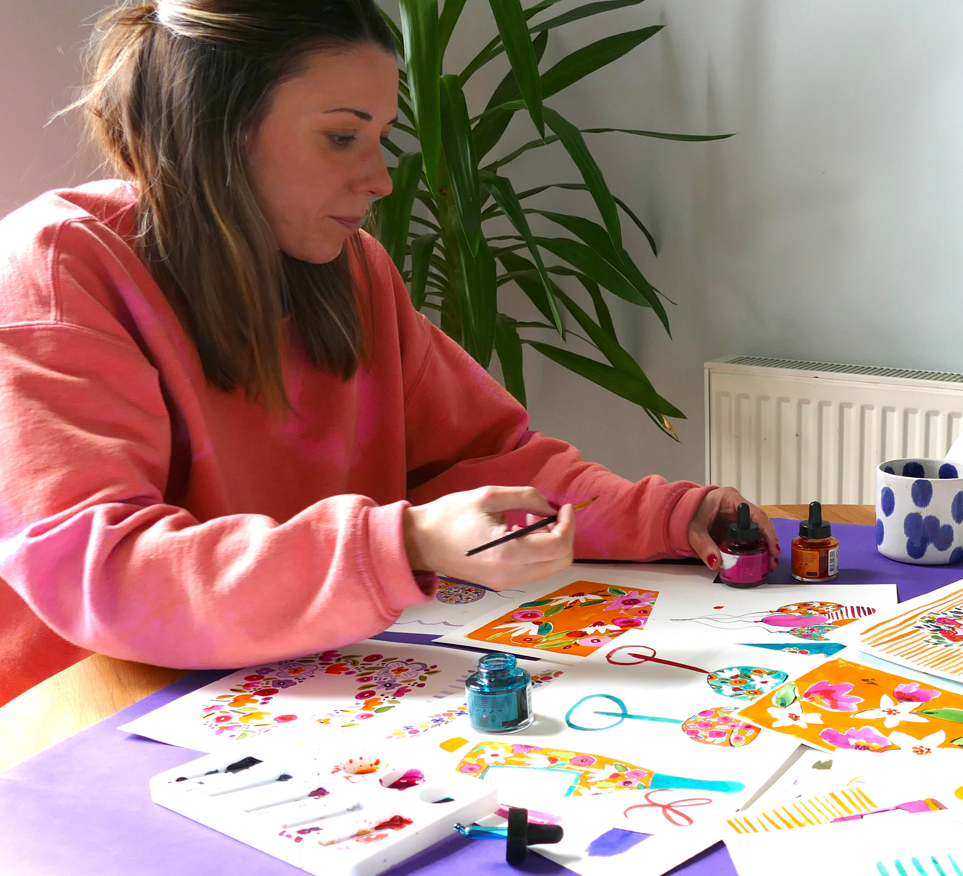 Kate in action creating artwork at her kitchen table