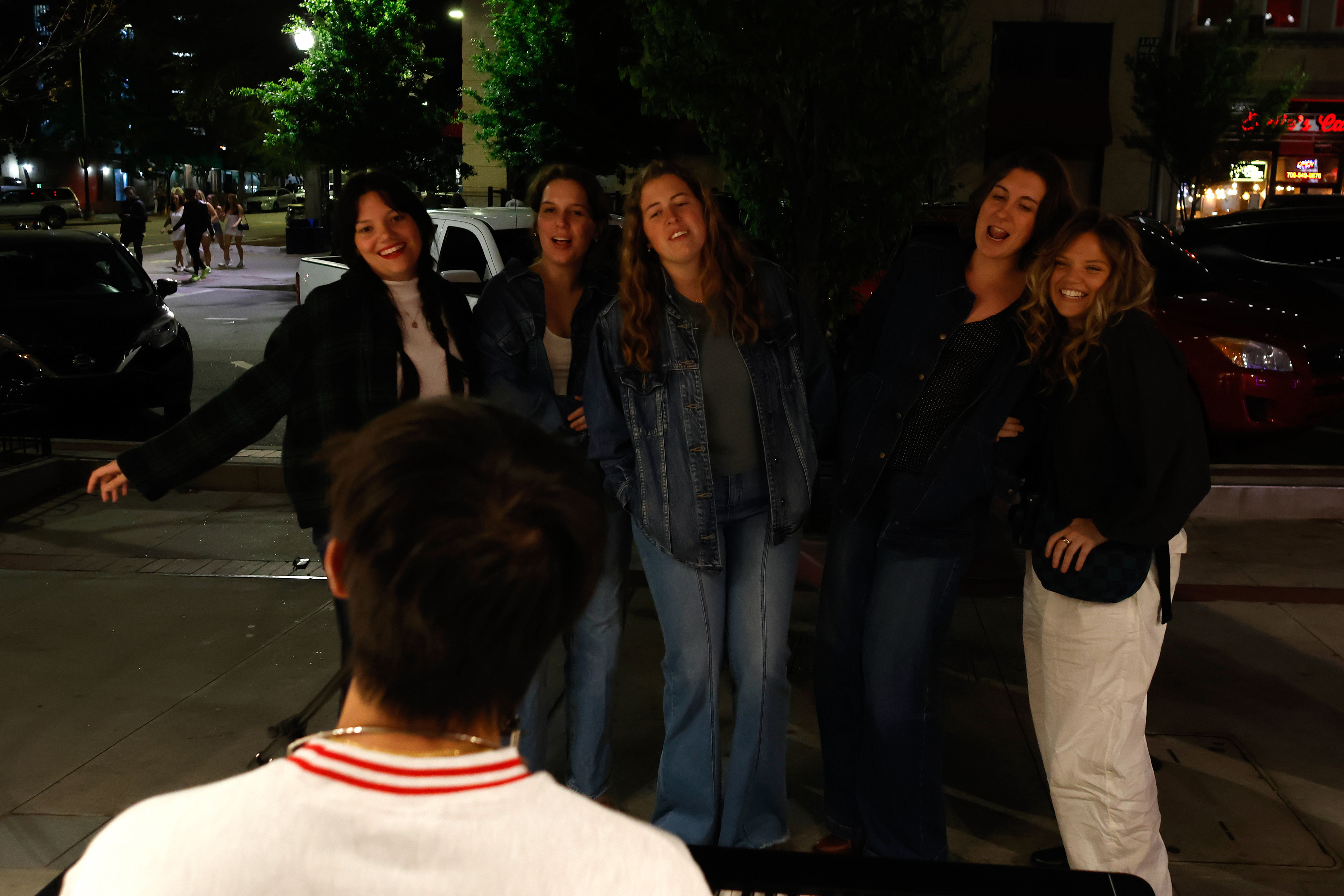 Hadley Short, Lolo McCreary, Kaelie Masaschi, Kate Lattner and Carly Anderson watch Andrew Hsu play the piano in downtown Athens, Georgia, on Friday, April 11, 2025. Hsu typically performs television themes or popular songs, such as "Pink Pony Club".