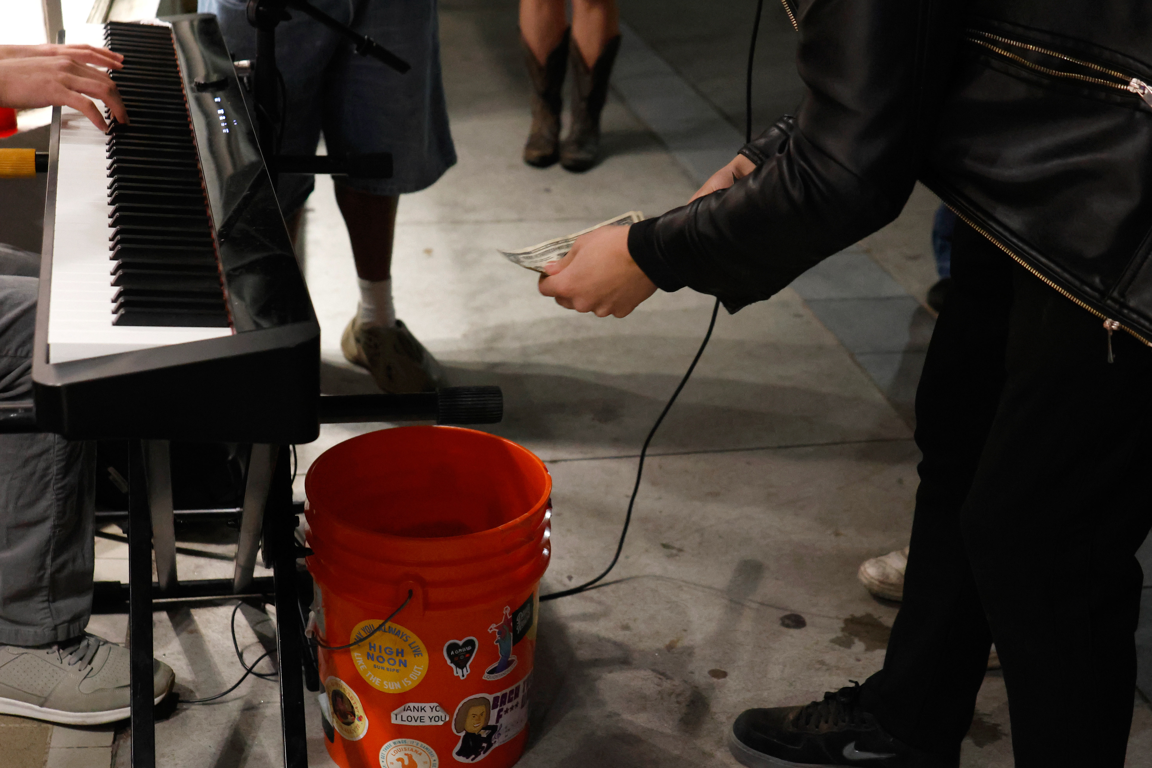 A spectator drops money into Andrew Hsu's donation bucket in Athens, Georgia, on Saturday, April 12, 2025. Hsu made $100 on the first night he started street performing in Athens.