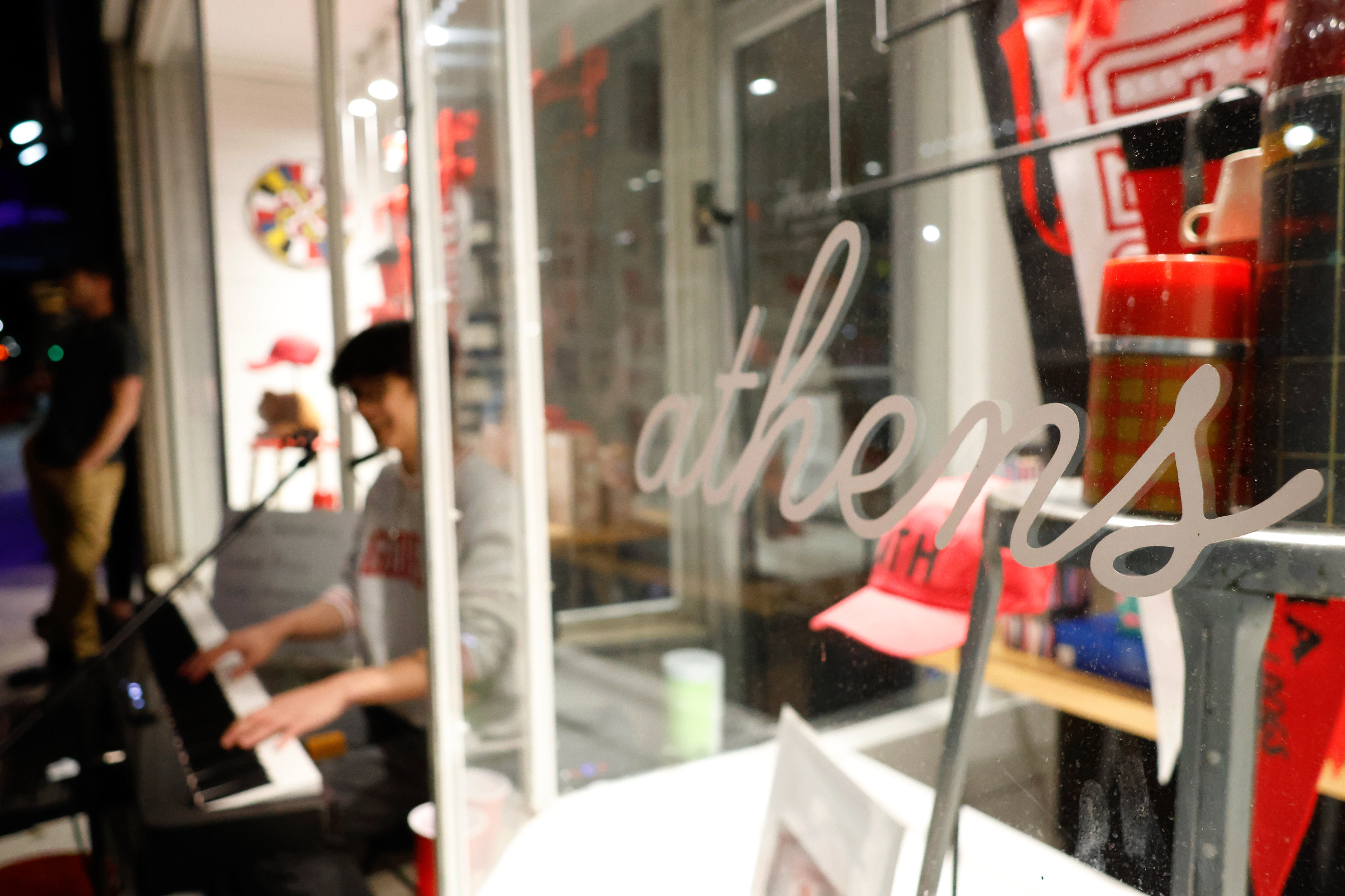 The word Athens is written on the window of Archer Paper Goods in Athens, Georgia, on Saturday, April 12, 2025. Andrew Hsu always street performs in the doorway of Archer Paper Goods.