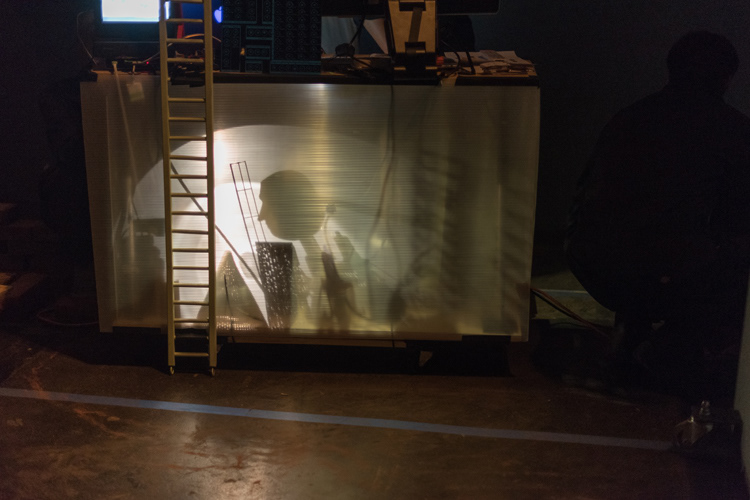 Puppet inspects sound booth with shadow play