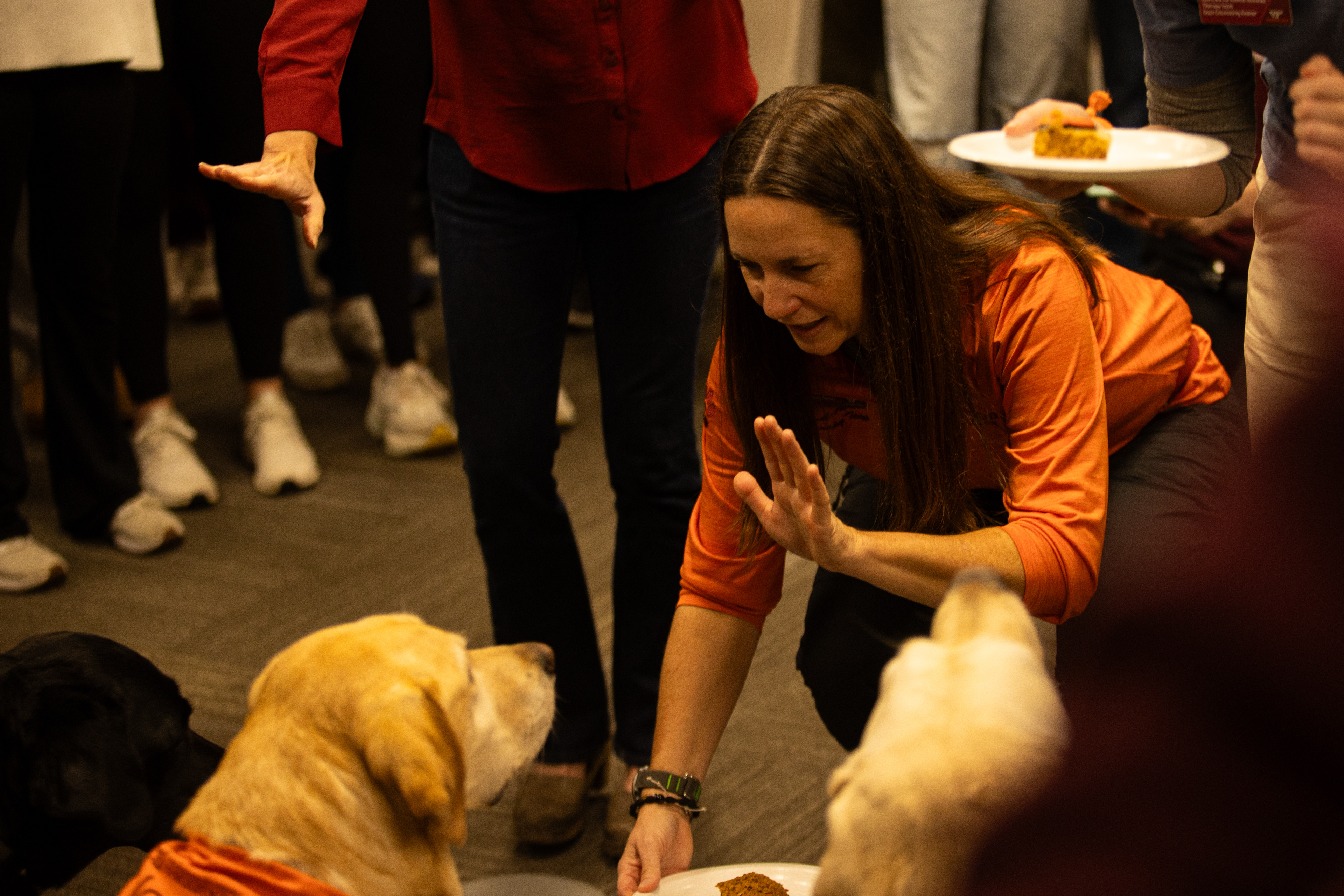 Josie’s handler, Rami Steinruck, along with others, signals Josie and the other dogs to wait until the singing concludes before eating their cake on Nov. 15, 2024. (Thomas Bray/JMC 4114)