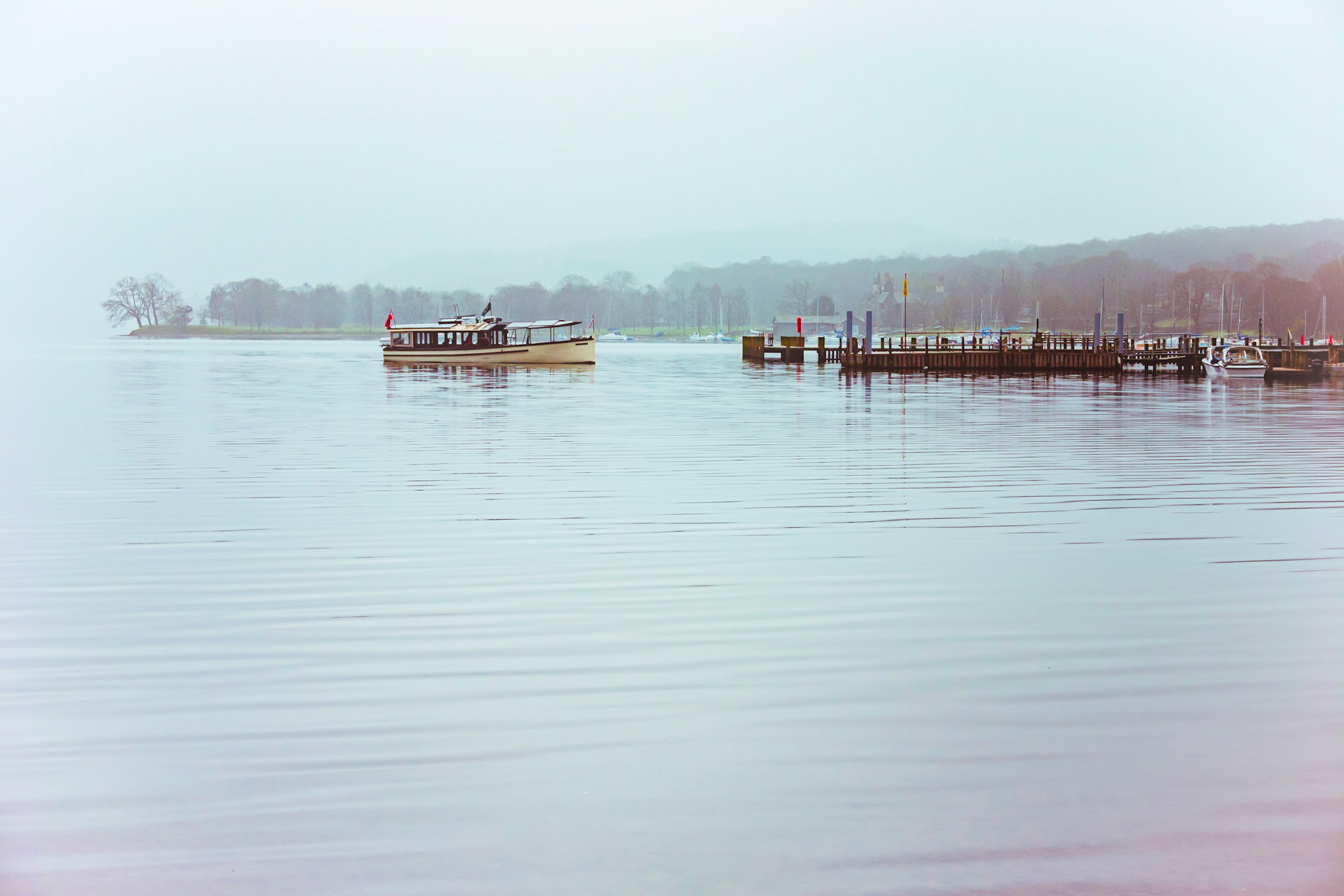 A toned image of the Ullswater lake ferry arriving at Pooley Bridge landing on a quintessentially quiet moody morning in the English Lake District National Park.