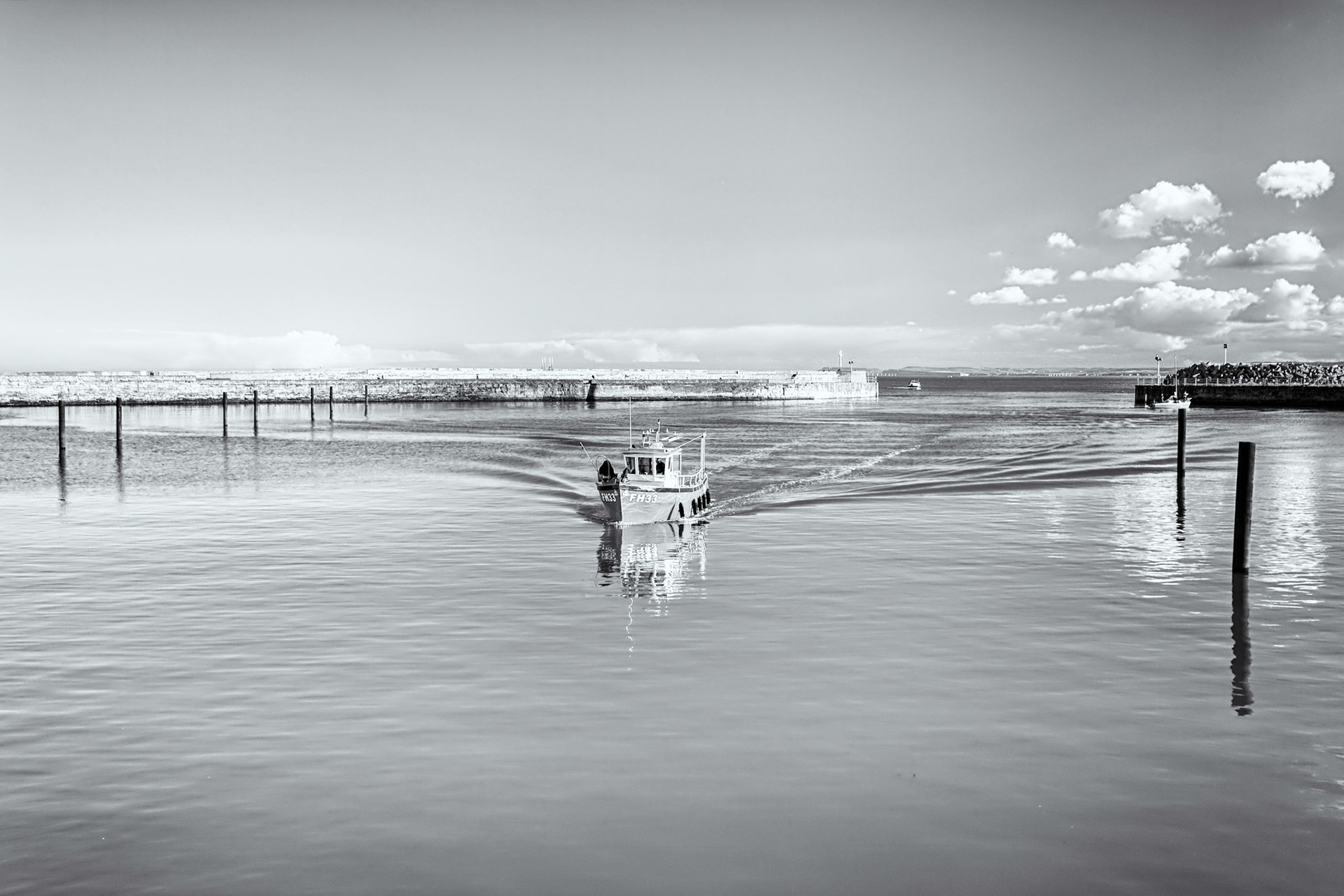 A lone fishing  boat disturbs the unusually still North Sea waters as it returns to port.Hartlepool in north-east England. 
