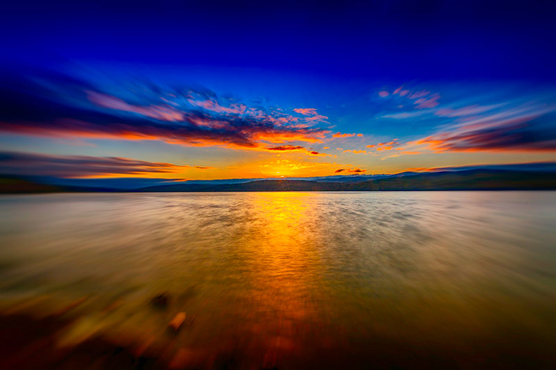The sun has almost gone for the day as it drops behind the distance mountains across Loch Rannoch in Scotland. Digitally manipluted blur and zoom effect.
