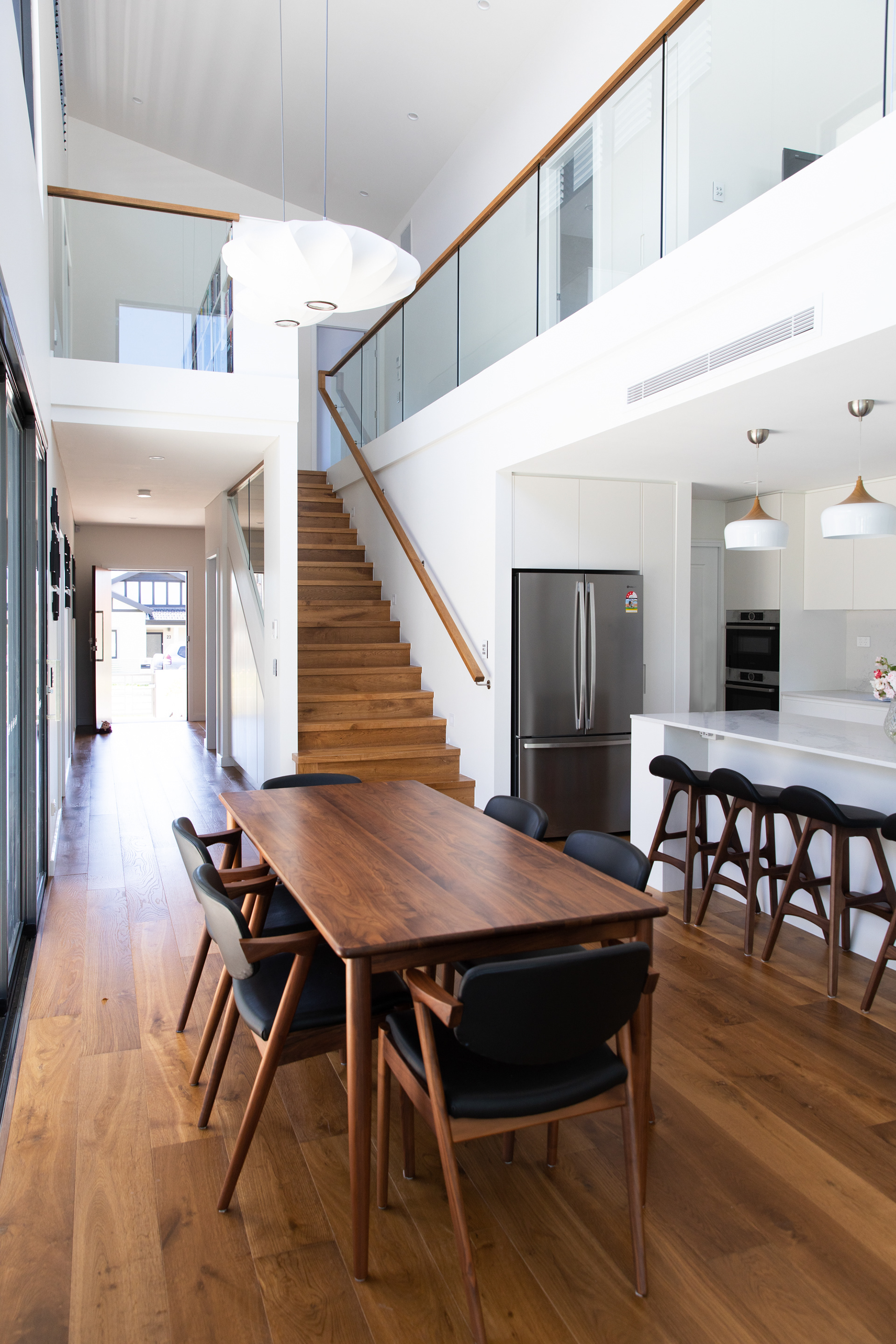 Light filled white interior with high raked ceilings is accentuated in the double height volume over the central kitchen and dining area.