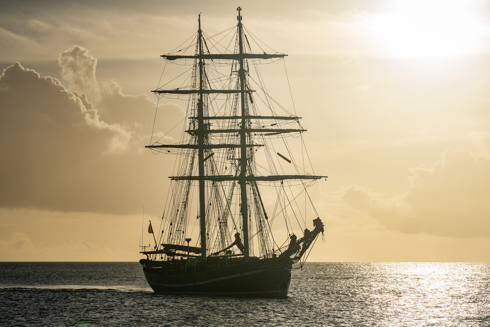 A tall ship drops anchor in Port St. Charles, Barbados amid the sunset haze
