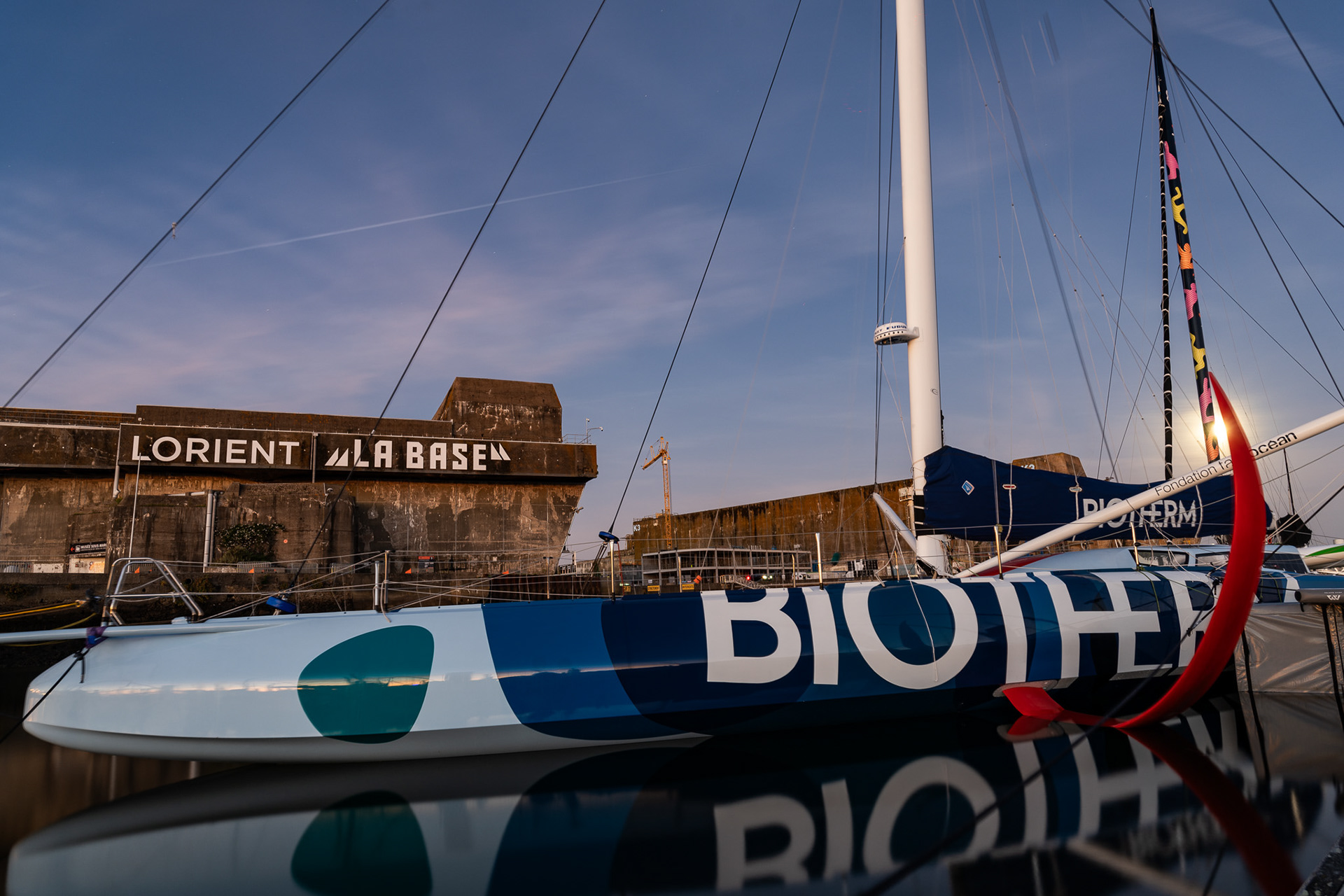 Paul Meilhat's Imoca Biotherm, with the full moon and historic World War Two era submarine bases in the background