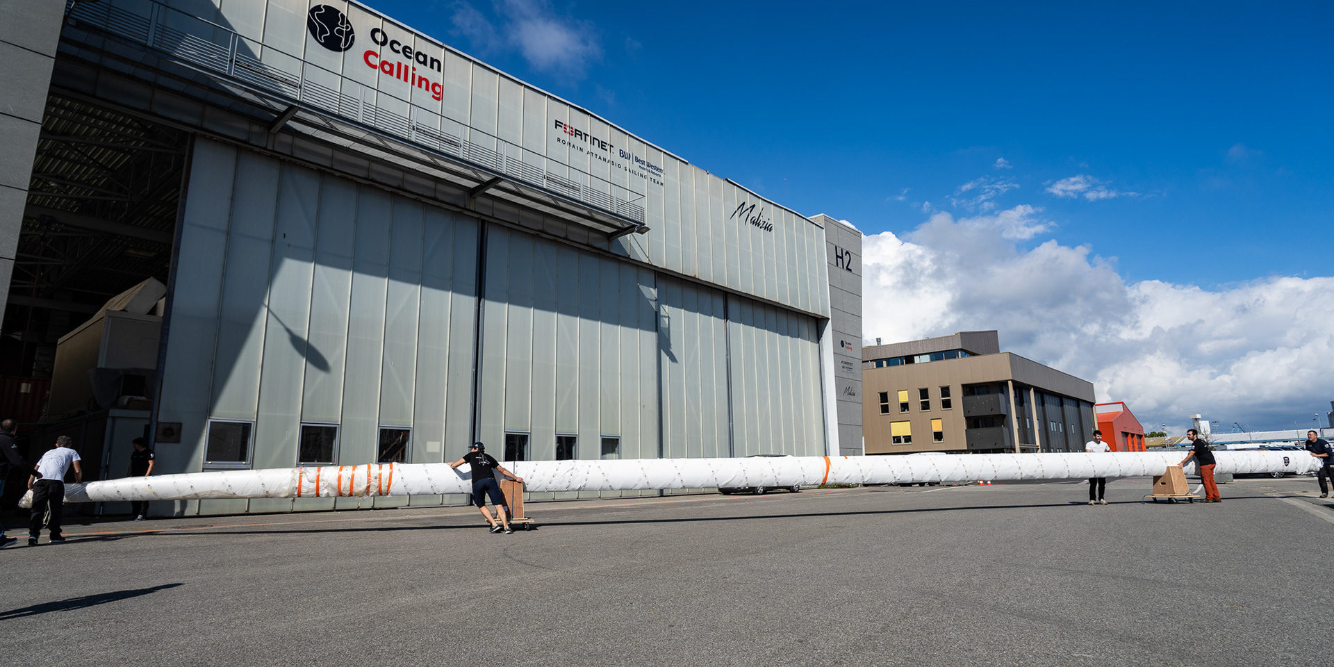 The monstrous 29-meter long mast is guided into the team's base