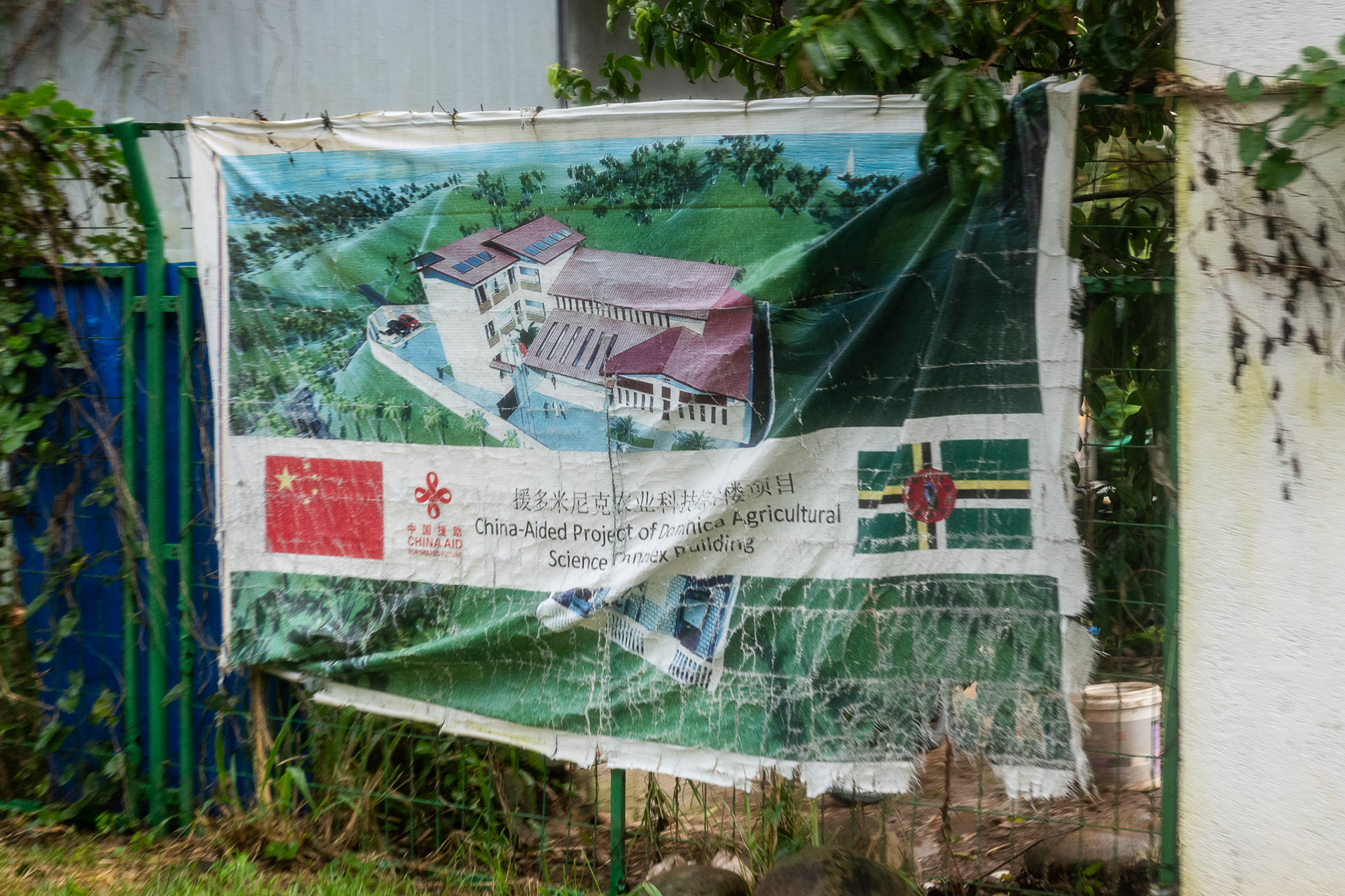 A sign along the road detailing a "China Aided Project of Dominica Agricultural Science Annex Building"