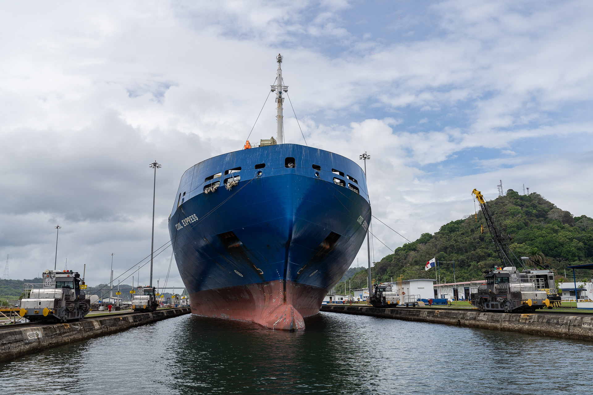 The Cool Express, an aptly named refrigerated cargo ship, pulls up behind our boat raft in the Pedro Miguel lock, aided by six silver locomotives.