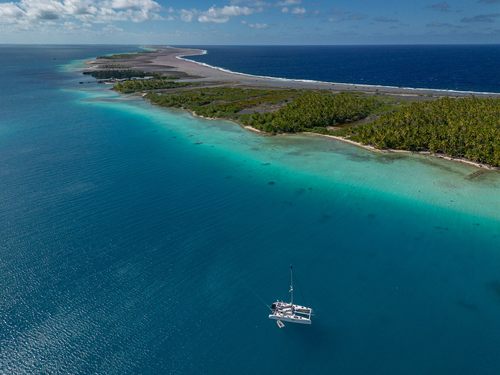 The dark blue Pacific ocean crashes against the barrier reef of Raroia