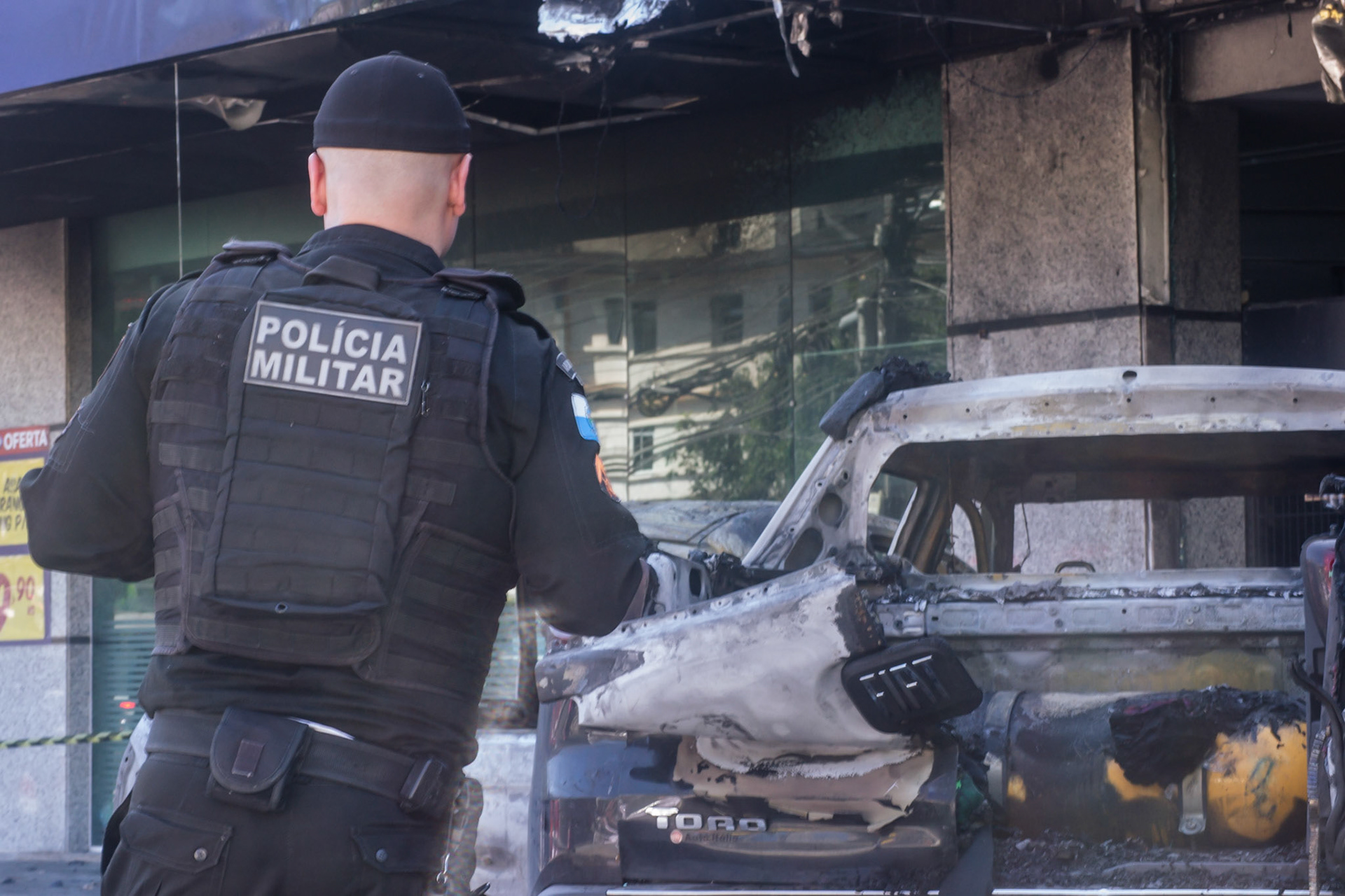 Policial observa veículo incendiado em estacionamento de mercado - Petrópolis (RJ), 9 de junho de 2023.