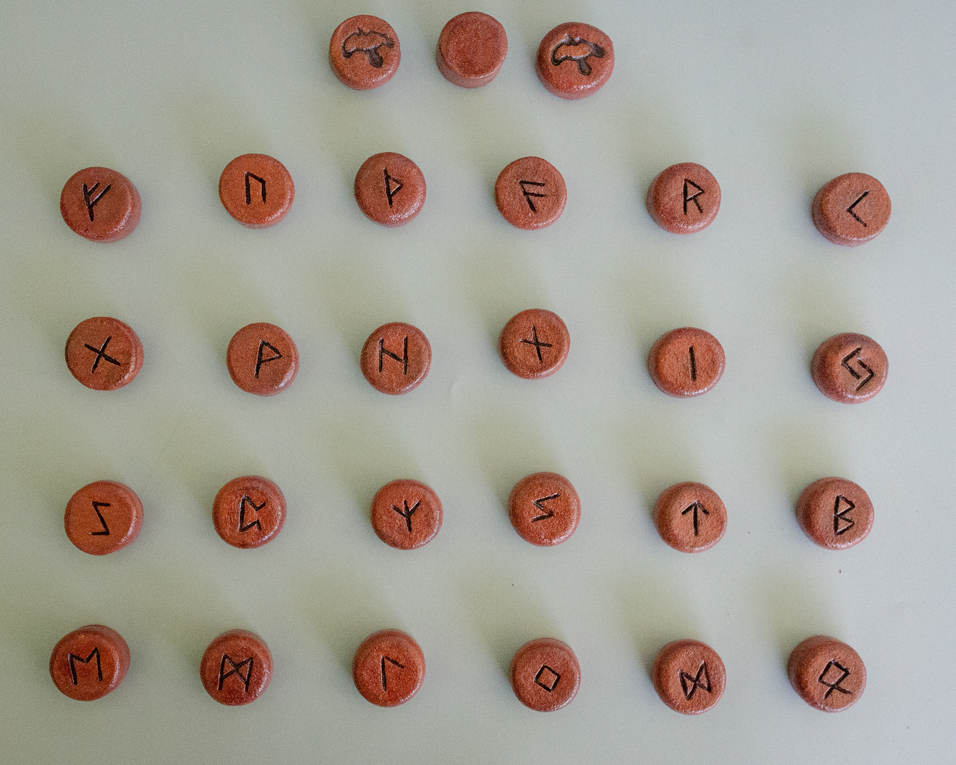 Elder Futhark Rune Stones & Raven stone (2024) Red Raku Clay with Red Iron Oxide and Porcelaine Paint 2cm (W) x 1cm (H)