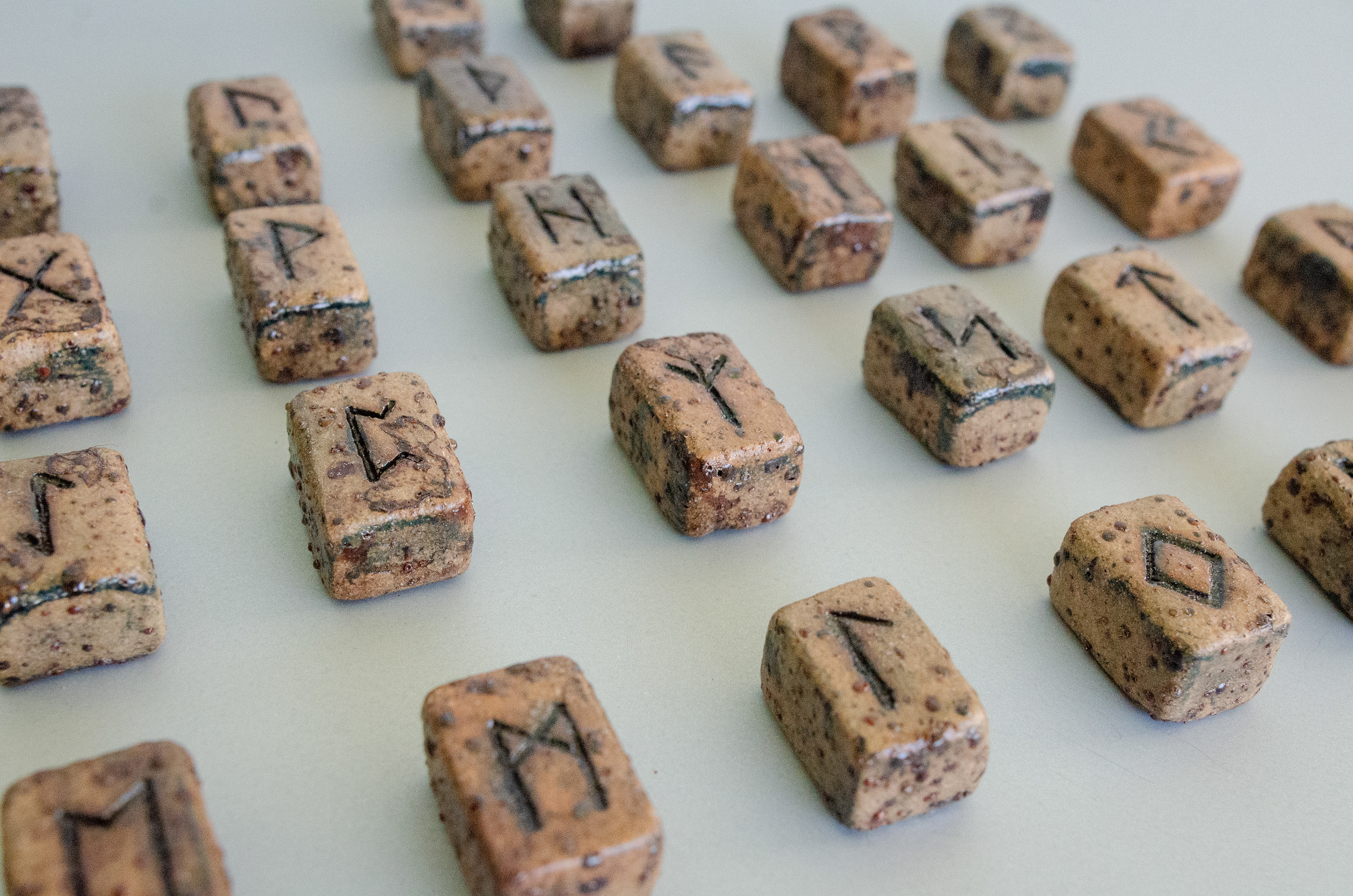 Elder Futhark Rune Stones & Raven stone (2024)  Buff Raku Trachyte with Red Iron Oxide & porcelaine paint 2cm (W) 1cm (H) 1cm(D)