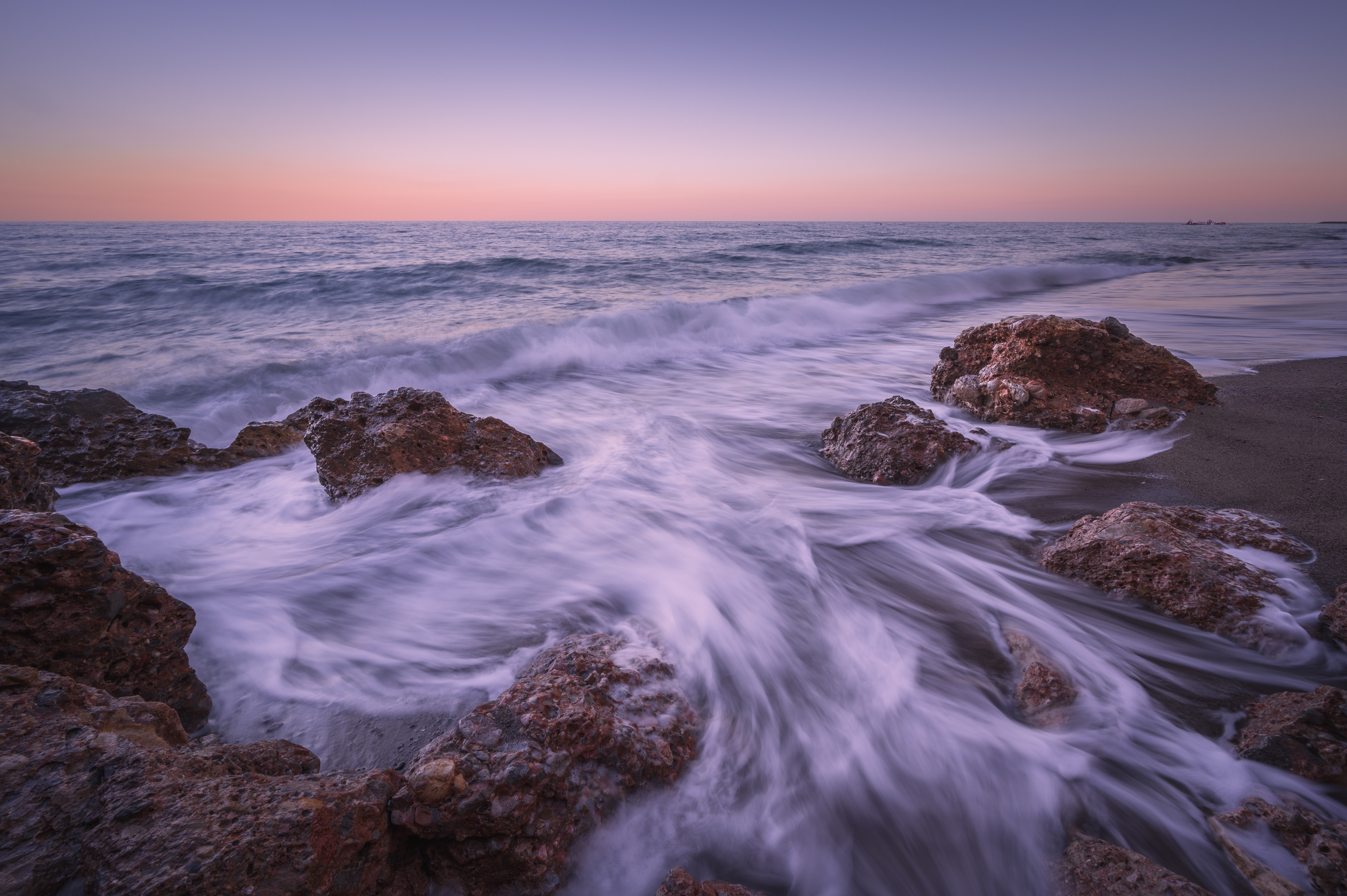 alt="Plage rocheuse en Espagne photographiée en pose longue au crépuscule"