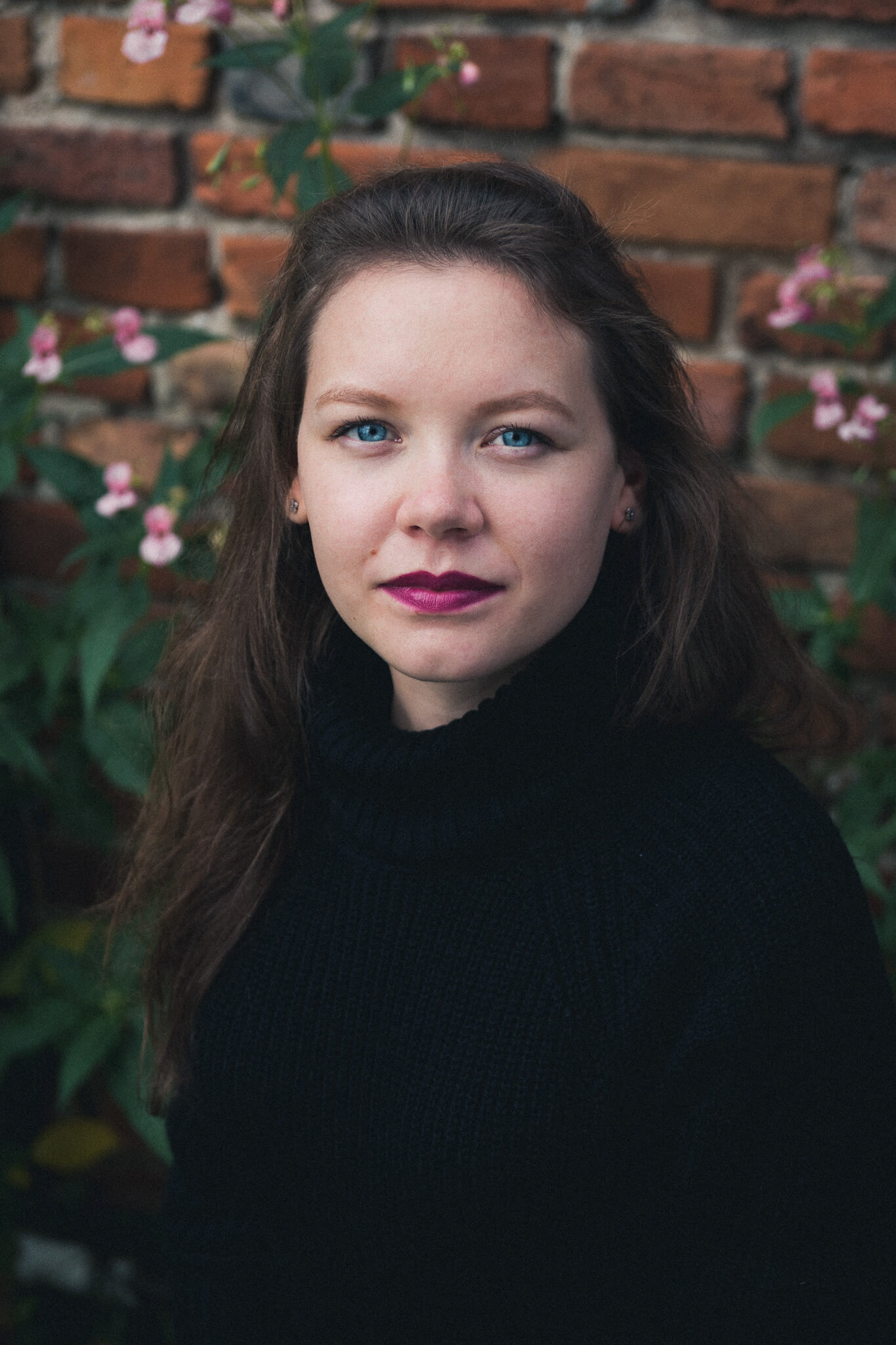 portret kobiecy Joanny, niebieskie oczy, rozmyte kwieciste tło