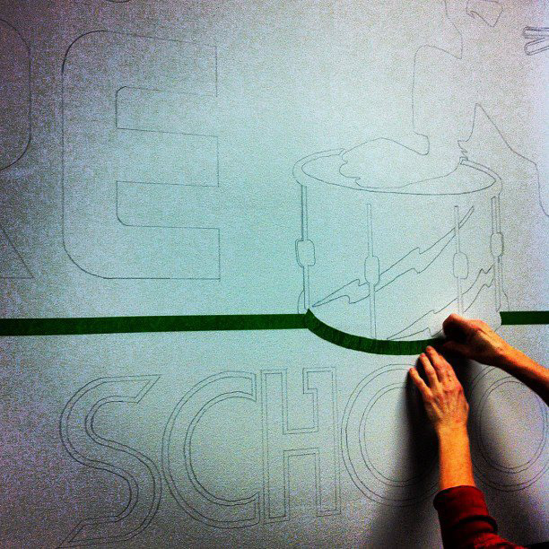Logo being painted onto the walls of the shop