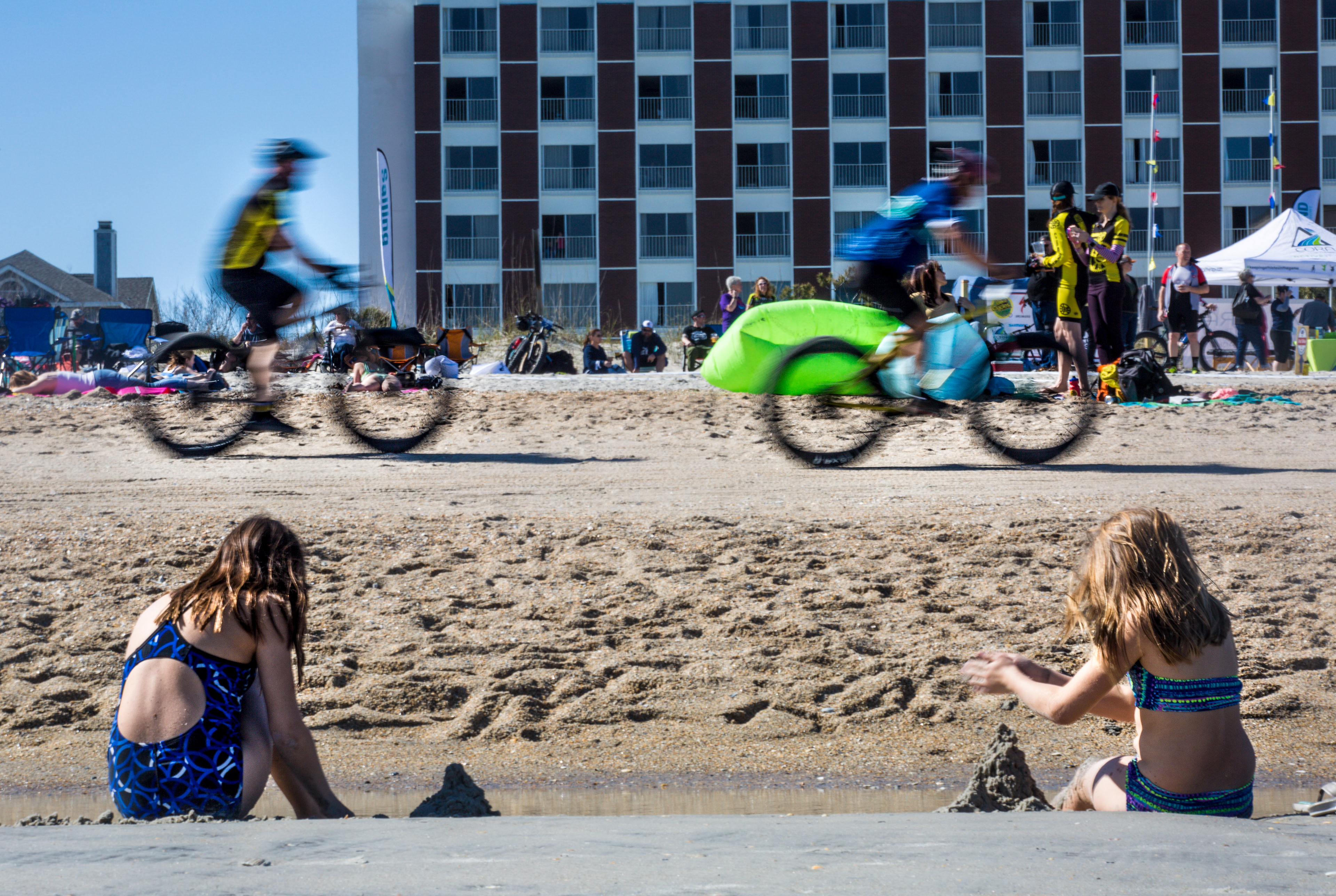 Beachgoer's build sand castles as cyclist's race by during the 2019 US Open Fat Bike Beach Championship at the Blockade Runner Beach Resort in Wrightsville Beach, NC, on Saturday, March 23, 2019.