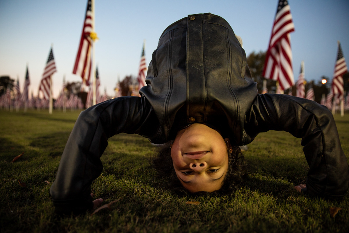 Fabiola Torres plays amongst American Flags at a memorial on Veterans Day, November 11, 2018, in Asheboro, N.C.