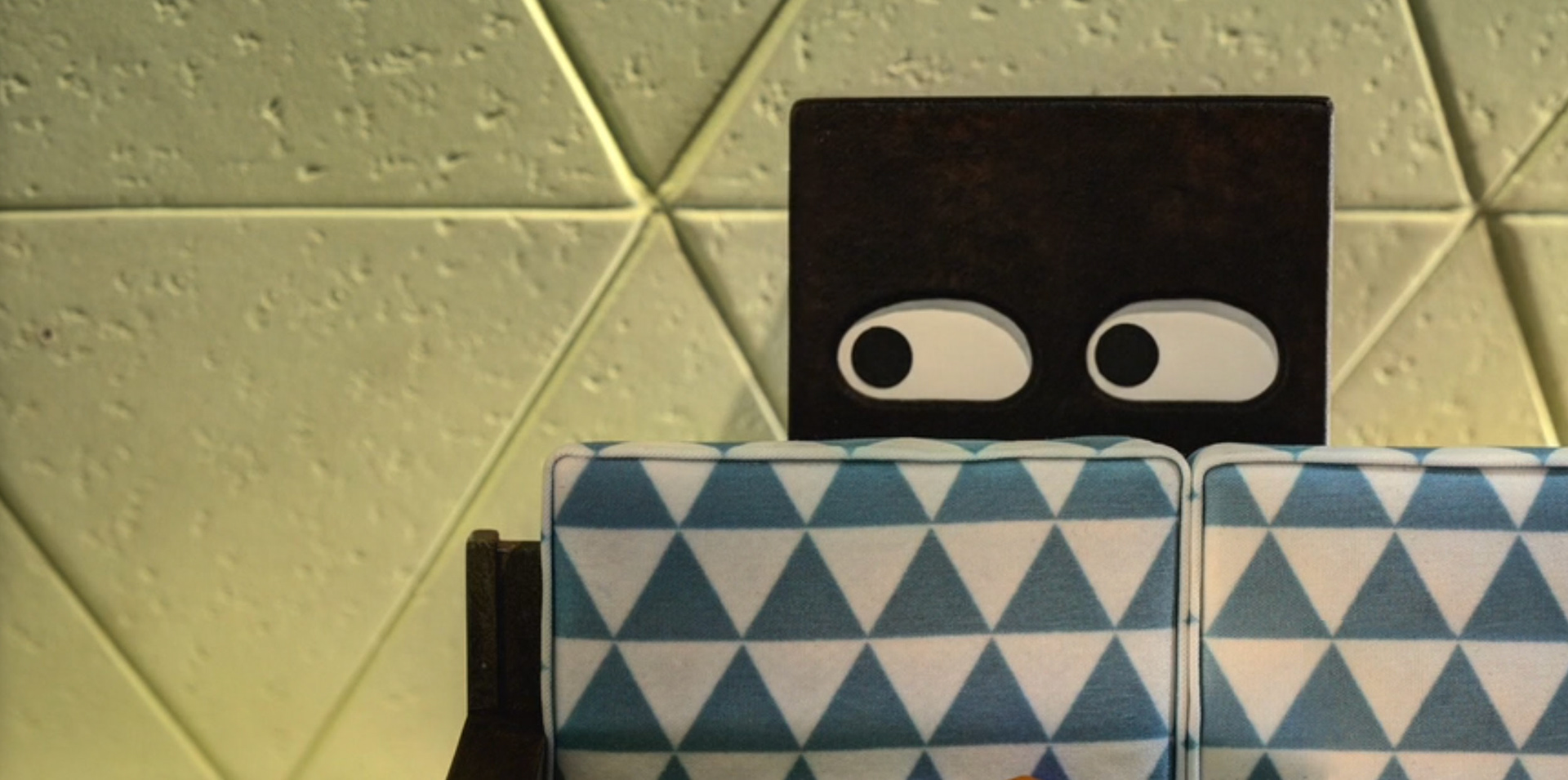 Square behind Triangle's couch - movie still