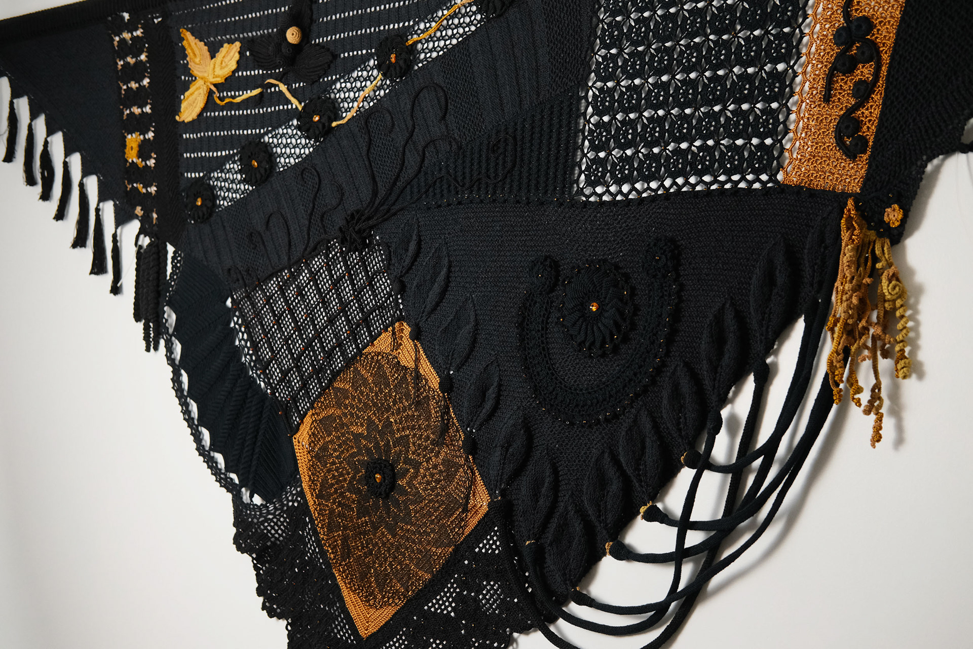 Detalhe da textura de "Desígnios", escultura têxtil de Cláudia Conde. Trama detalhada com fios em tons terrosos e crus, destacando técnicas ancestrais de tecelagem manual.