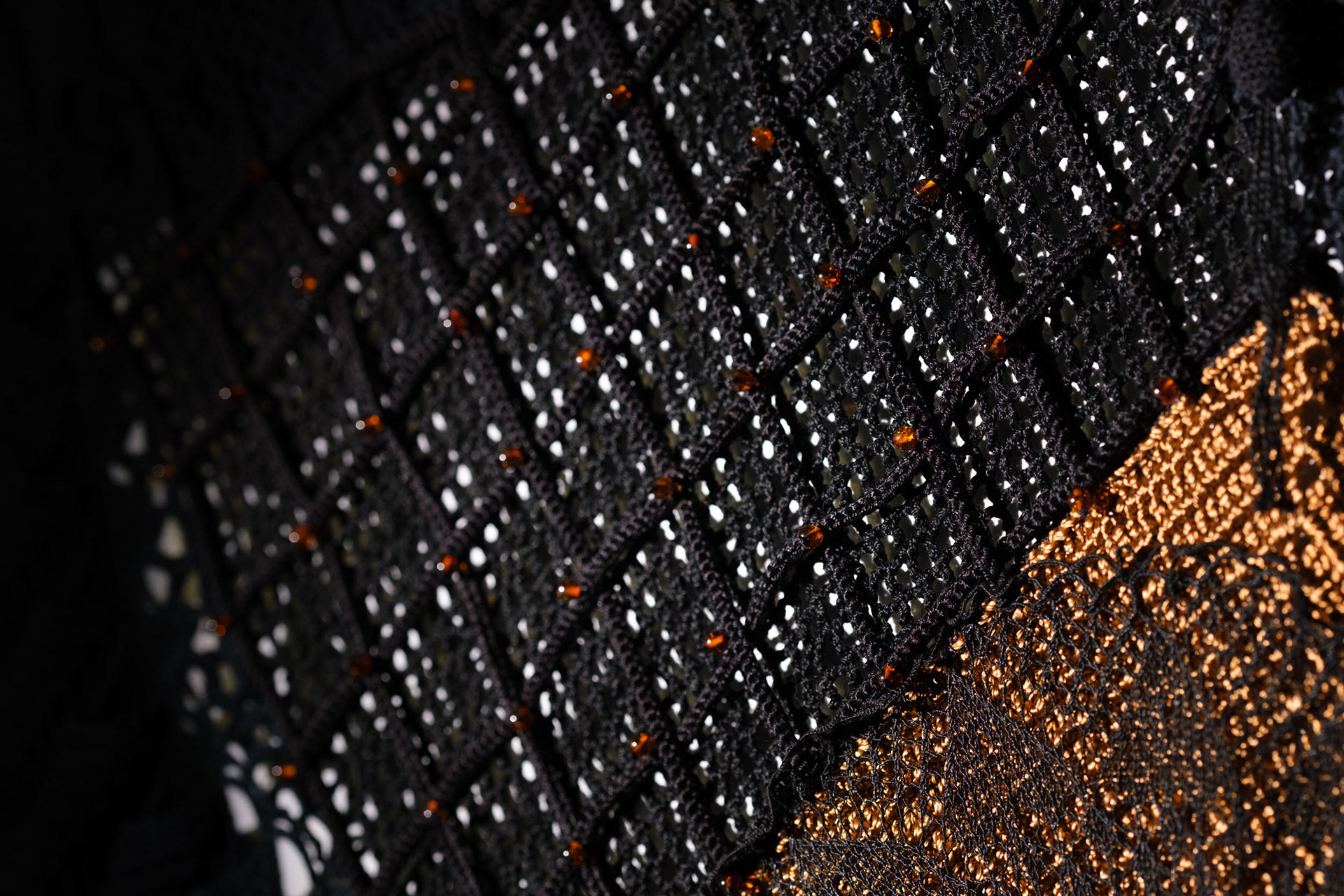 Detalhe da textura de "Desígnios", escultura têxtil de Cláudia Conde. Trama detalhada com fios em tons terrosos e crus, destacando técnicas ancestrais de tecelagem manual.