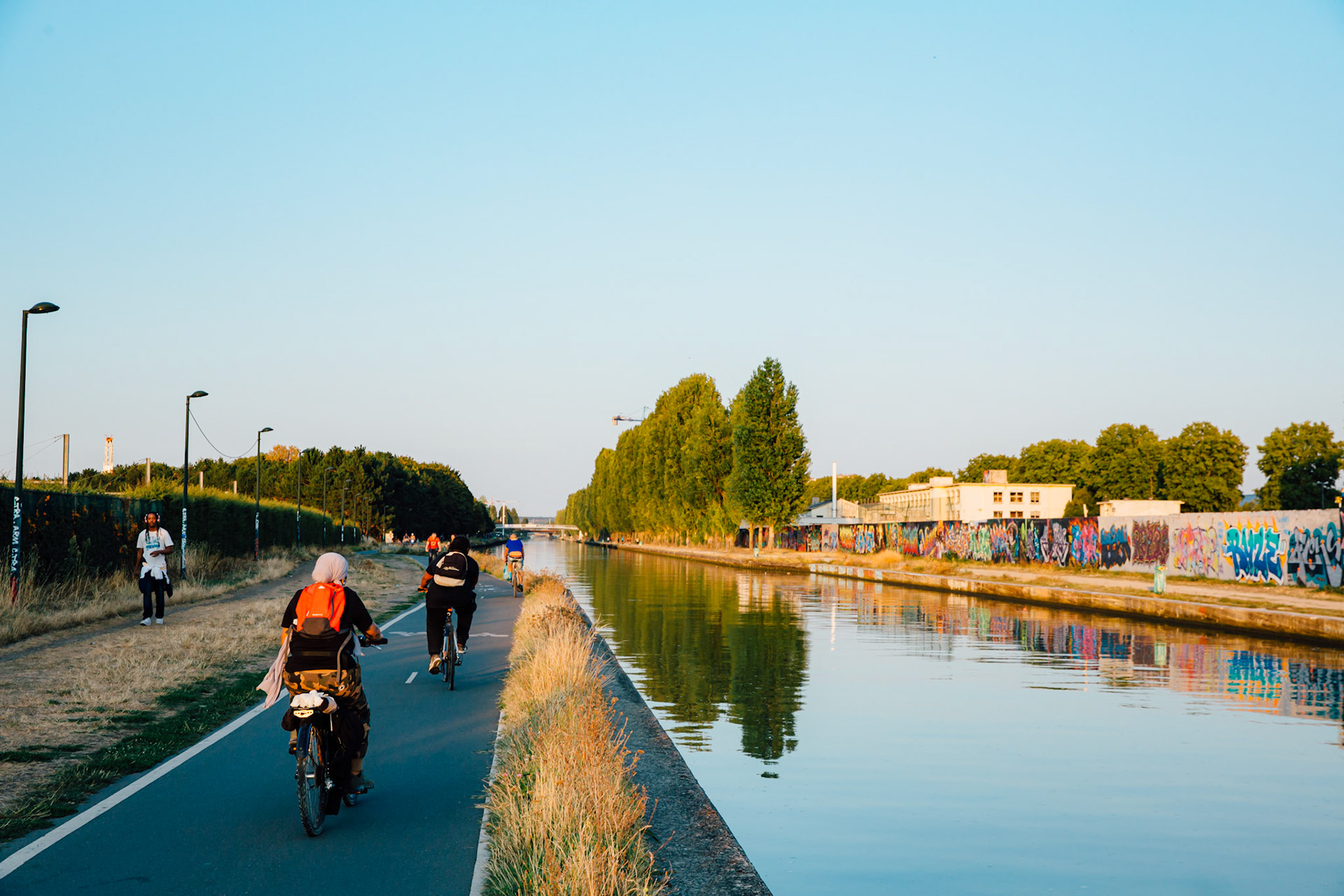 Vision du canal et de sa piste cyclable au niveau de Bobigny. On peut apercevoir à droite de nombreux murs avec des graphitis, les zones industrielles, et lieux de dépôts en tout genre sont très présents. Toute cette partie semble à vélo très transitoire, avec peu d’accès direct sur des lieux résidentiels aux alentours.