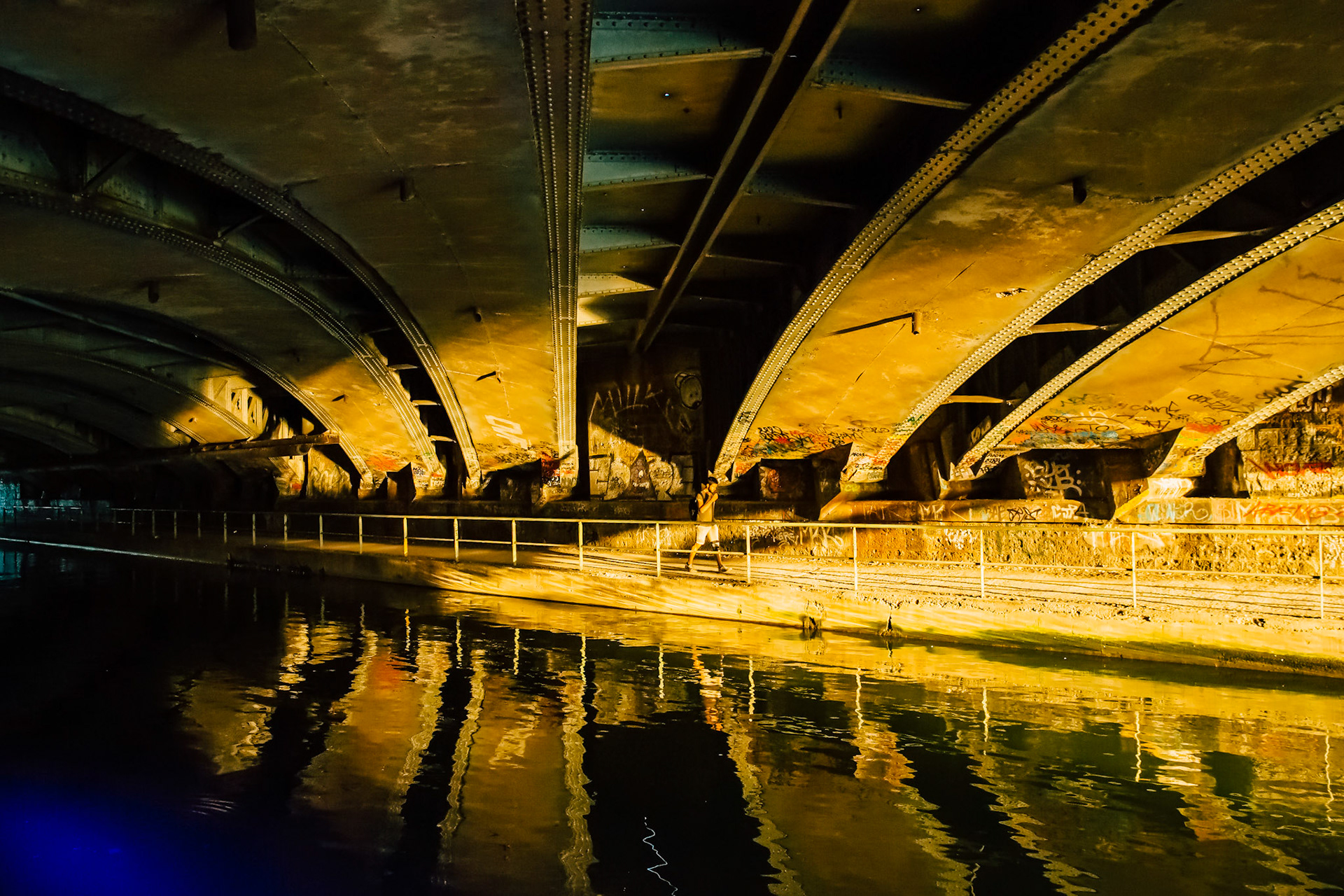 C’est la Golden Hour, le soleil se rapproche de l’horizon, donnant une texture surréaliste sur la voute d’un pont avec les reflets dorés dans l’eau.