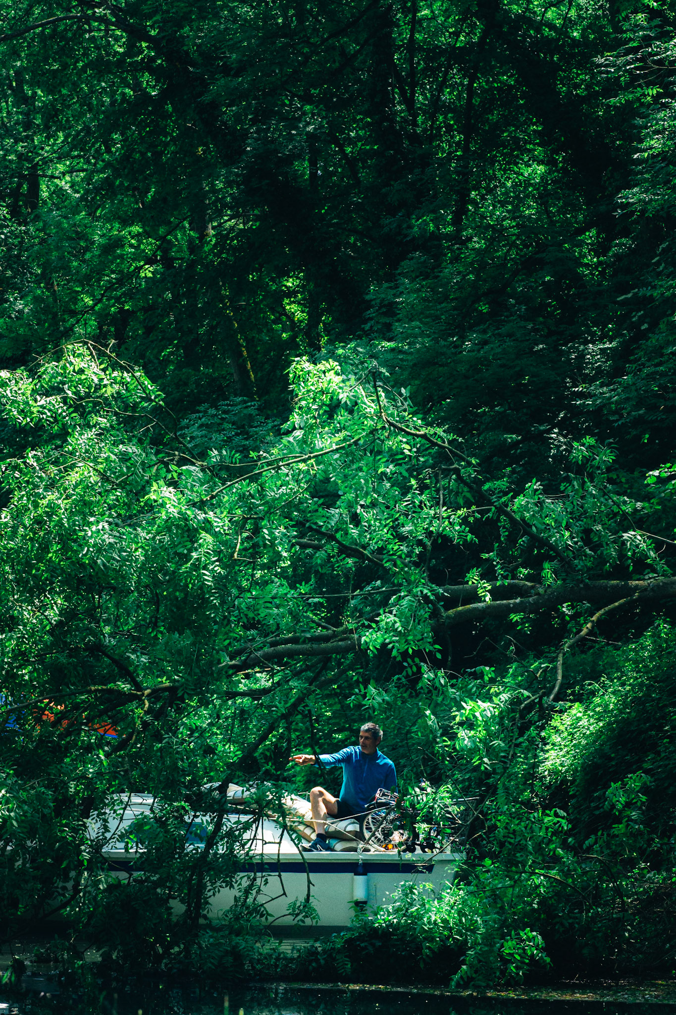 L'arbre déraciné barre la route aux rares voyageurs fluviaux. Laurent sur son bateau, à l'allure héroïque, se fraie un chemin, et casse à main nu les branches faute de mieux.