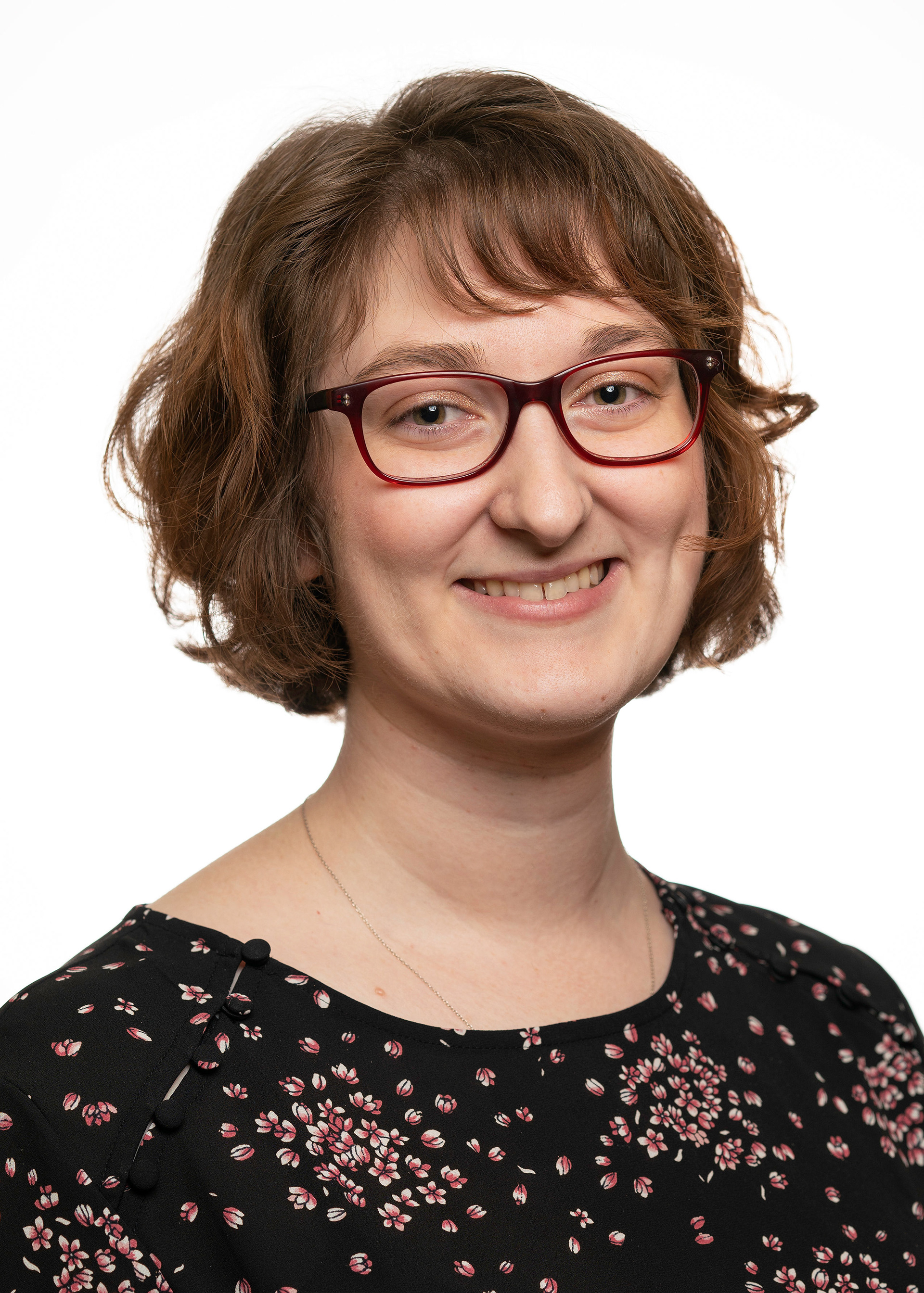 Photo of Nora Lindner. She has short, brown, wavy hair and red glasses.