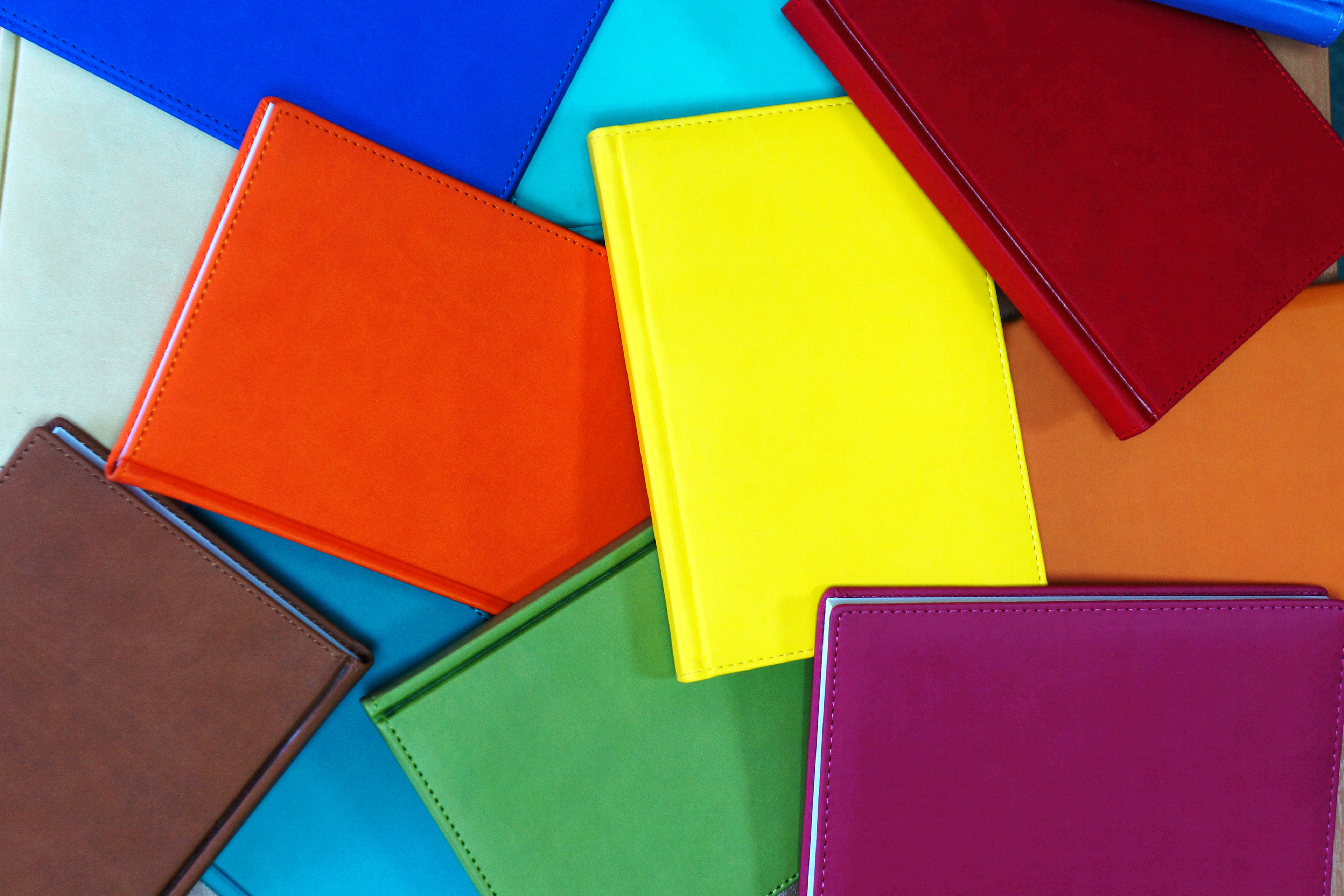 Photo of pile of rainbow-colored books scattered across a table.