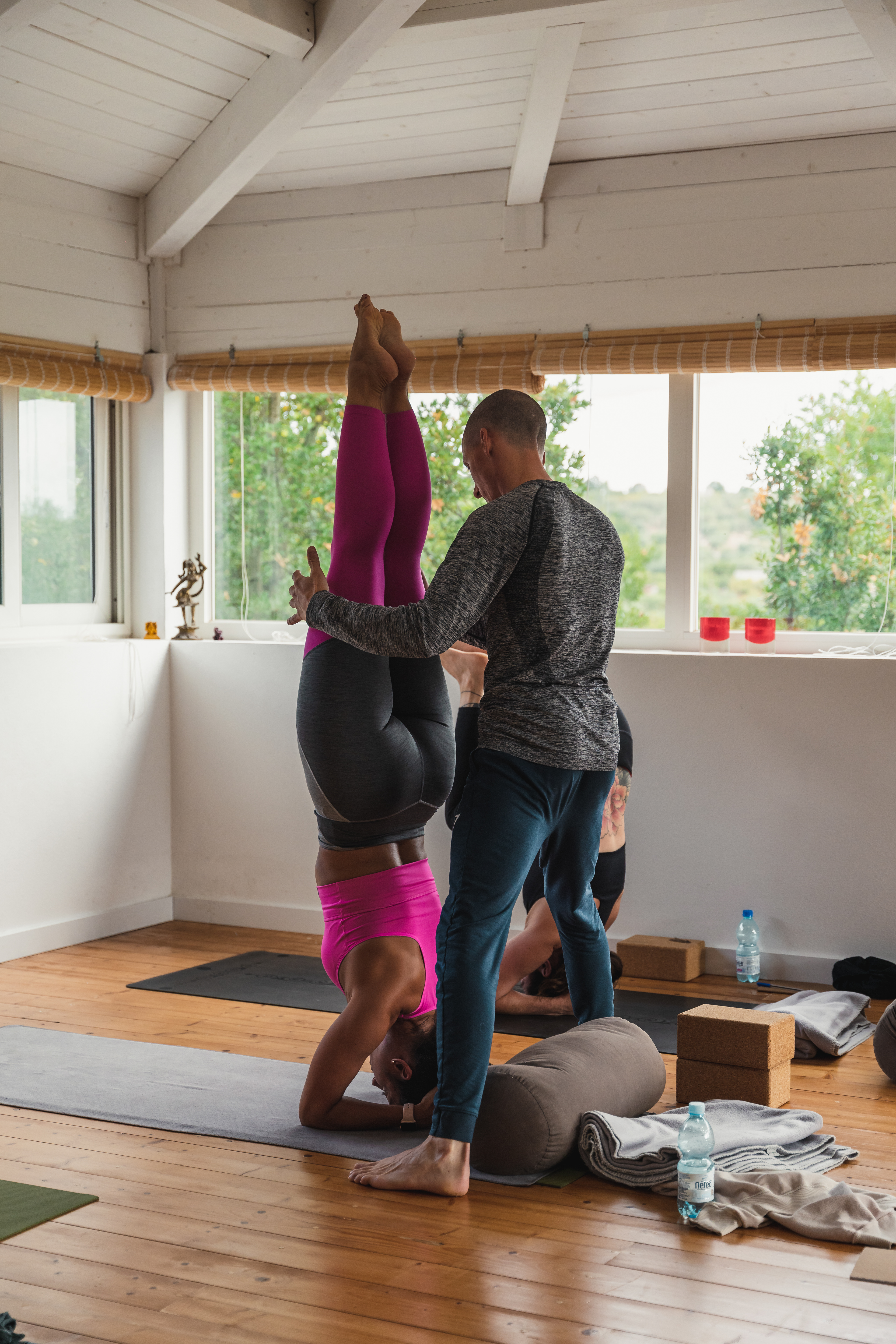 Patrick assisting a student in headstand during a workshop