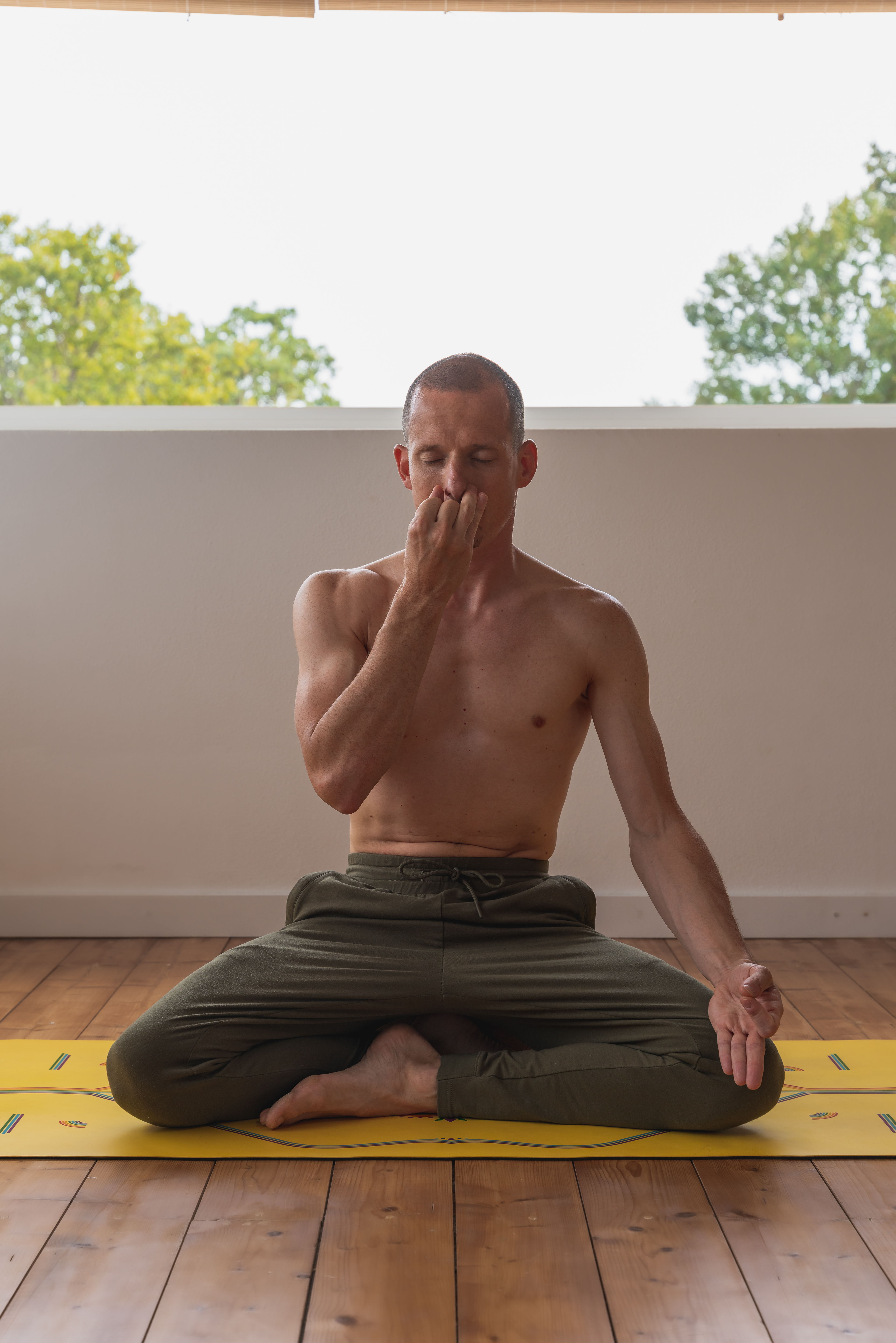 Patrick sitting in cross legged seat practicing nadi shodona pranayama