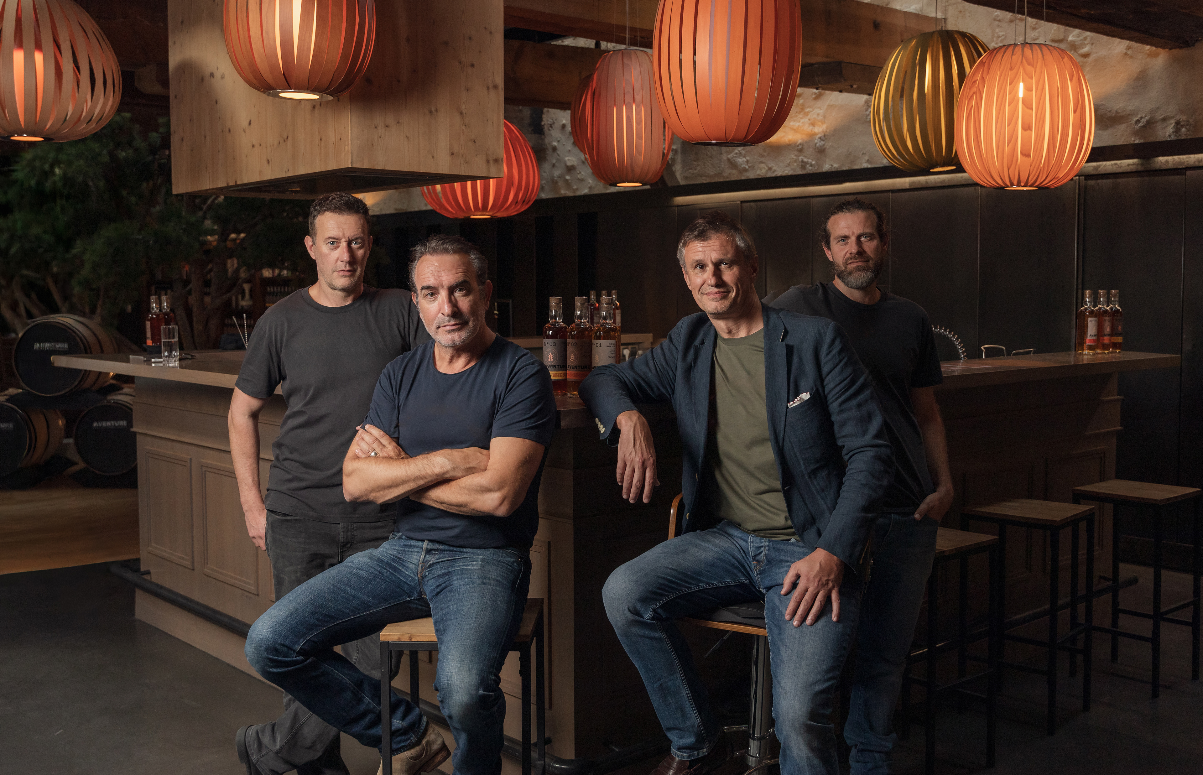 jean dujardin assis avec ses associés de la marque Aventure whisky 