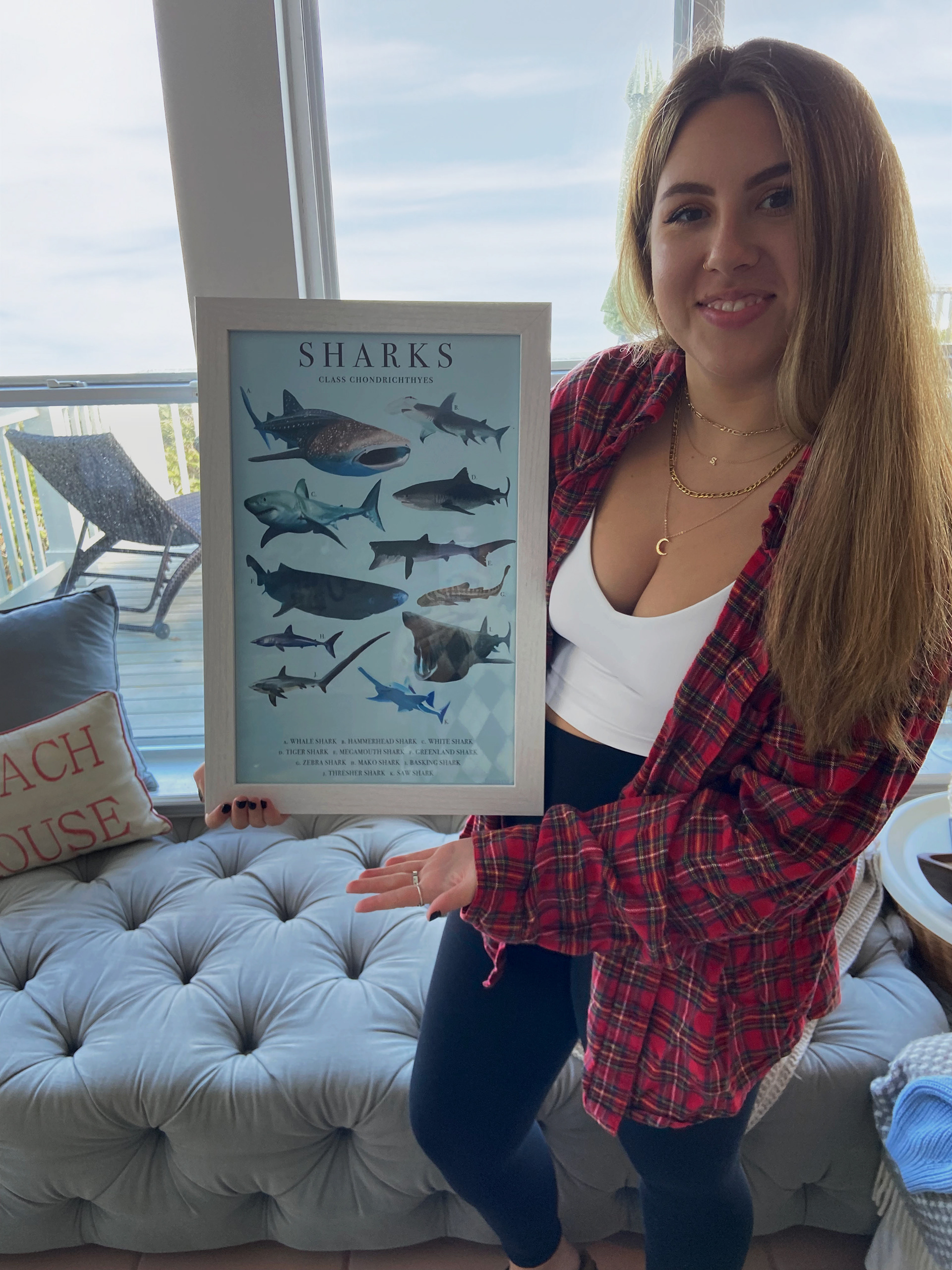 a woman holding a framed shark poster
