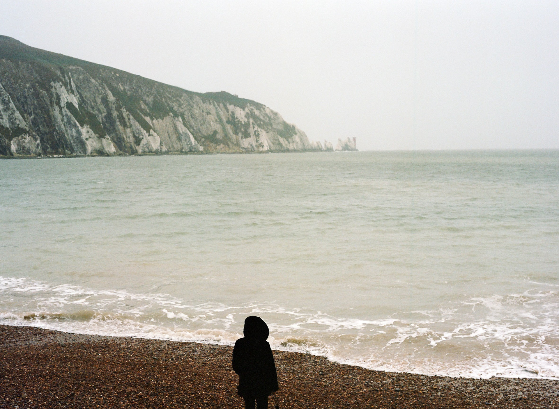 A figure looks out to The Needles at Alum Bay, Isle of Wight. A medium format photograph taken by Bristol based photographer Jake Hitchcock.