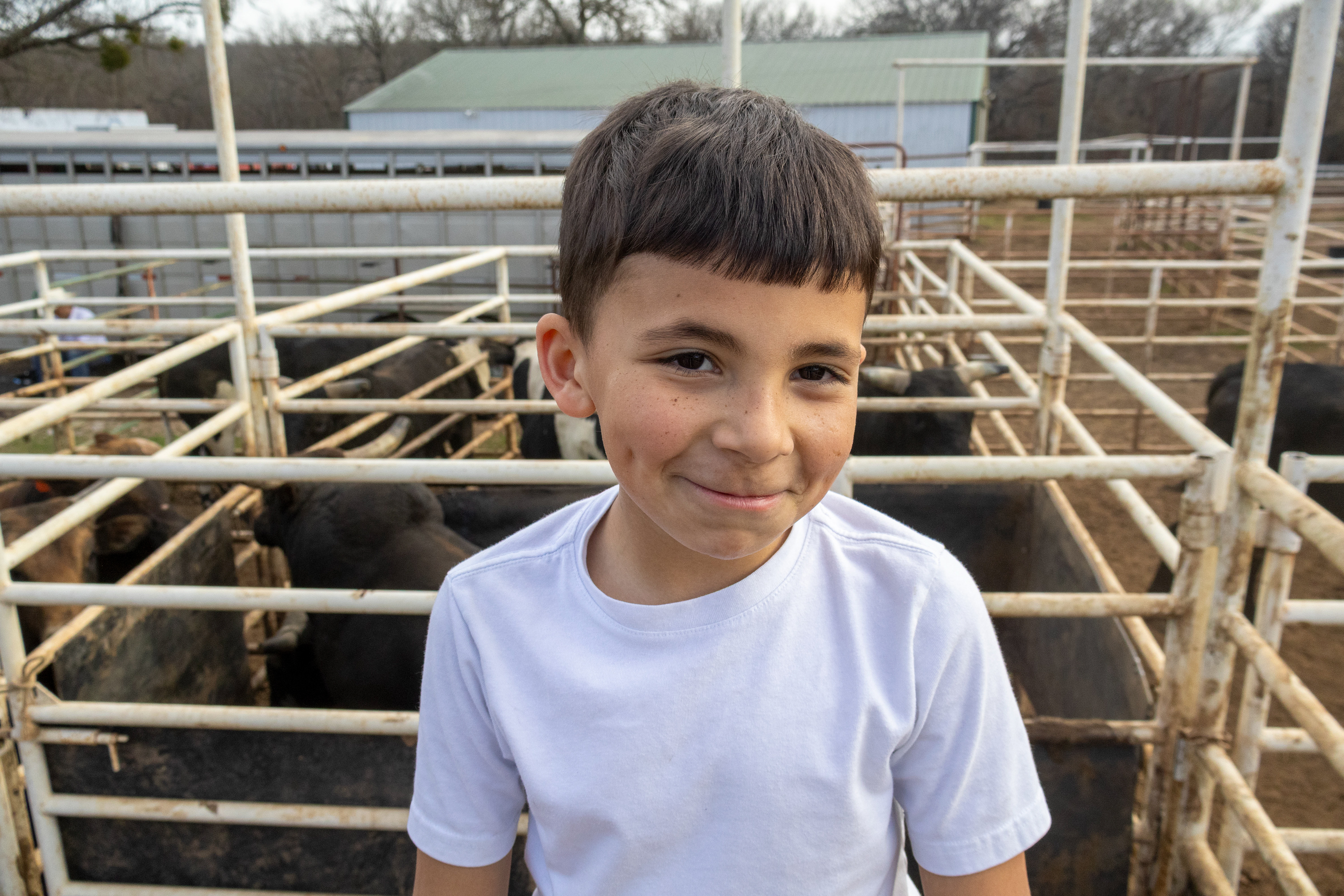 Taiten Roberts, 8, stands in the holding pens at 4B Brantley Ranch, smiling at the camera. Lauren Sicking