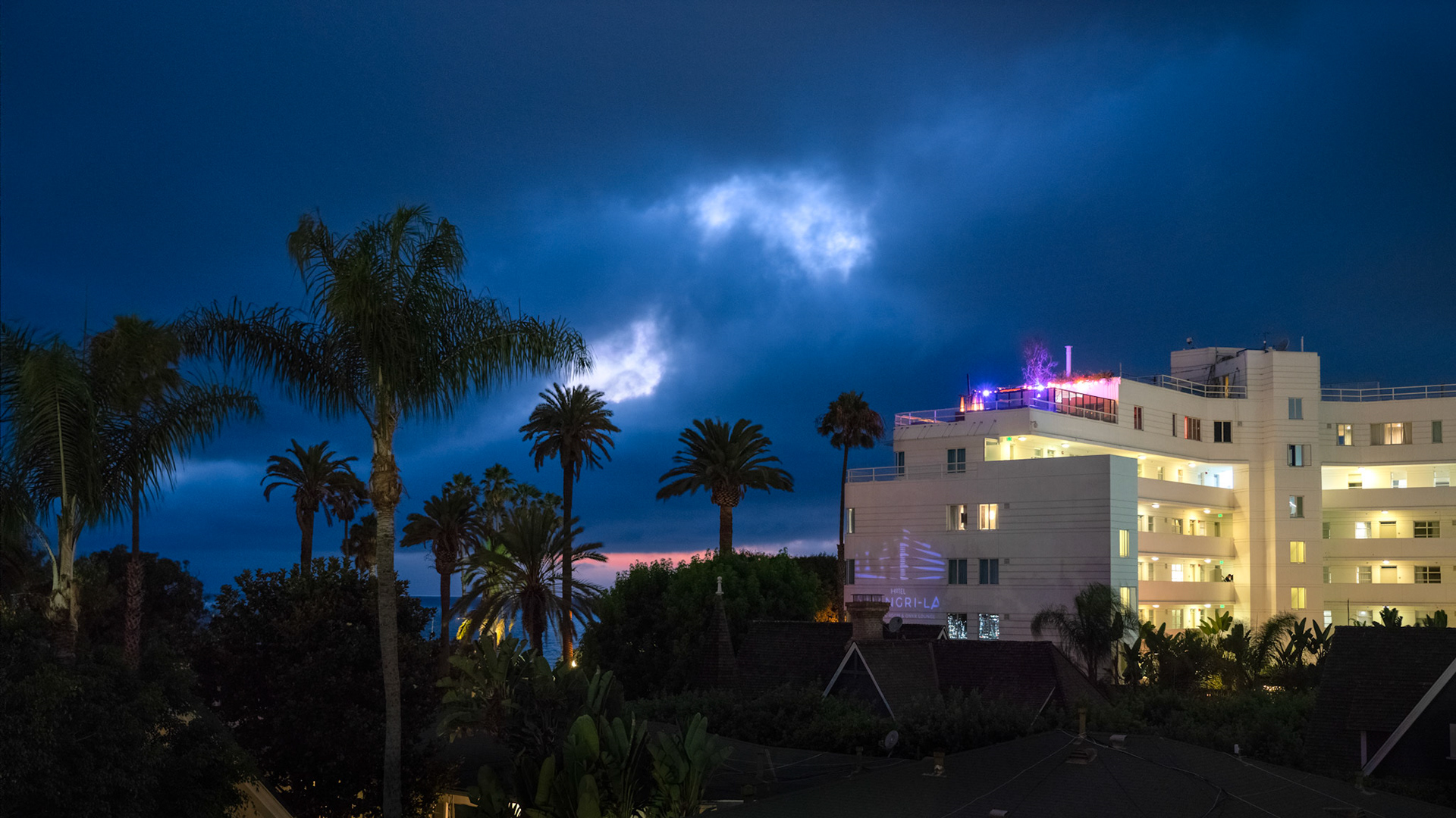 Handheld night photography – Hotel Shangri-La in Santa Monica in blue hour. While we were enjoying some great food at Elephante, the skies suddenly turned ominous, the wonderful warm summer nights that we have been enjoying for the last several weeks giving way to a breezy and cold fall night (although technically it is still summer). And then light peeked through couple holes in the clouds with the sunset glow still visible on the horizon. Not having a tripod, I set up the camera to manual, f/4.0, 1/40 sec, ISO 6400 and took 8 quick shots in succession to later merge into a stack mean in Photoshop. The resulting photo is remarkably sharp and low noise, capturing the exact mood. Hope you like it.